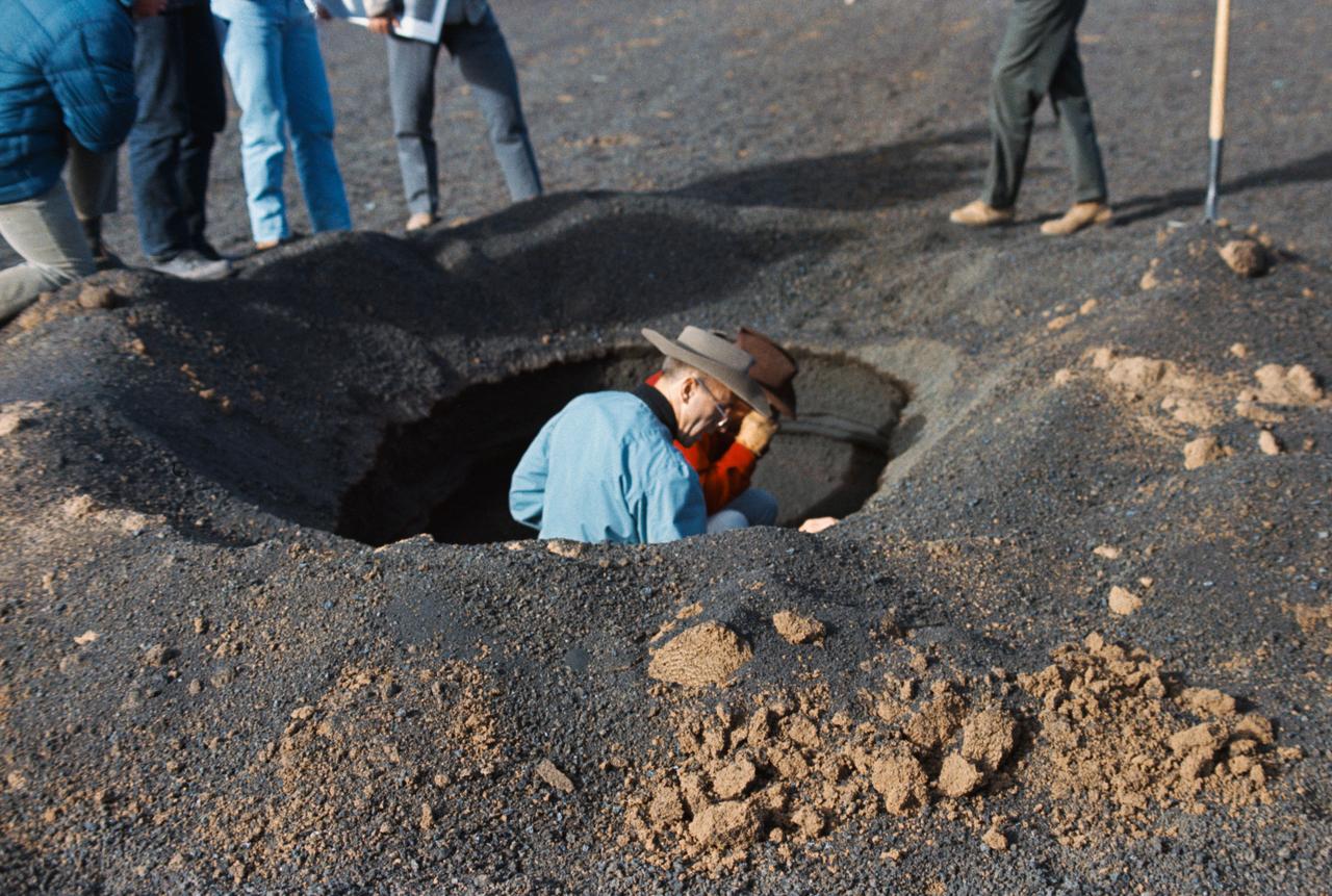 S69-55662 (10 Oct. 1969) --- Astronauts Alan L. Bean (left) and Charles Conrad Jr., the two crewmen of the Apollo 12 lunar landing mission who are scheduled to participate in two lengthy periods of extravehicular activity (EVA) on the lunar surface, are pictured during a geological field trip and training at a simulated lunar surface area near Flagstaff, Arizona. Here Conrad, the Apollo 12 commander, gets a close look through hand lens at the stratigraphy (study of strata or layers beneath the surface) of a man-dug hole, while Bean, the Apollo 12 mission's lunar module pilot, looks on. The topography in this area, with several man-made modifications, resembles very closely much of the topography found on the lunar surface. While Conrad and Bean explore the lunar surface (plans call for Apollo 12 spacecraft to land in the Sea of Storms), astronaut Richard F. Gordon Jr., command module pilot for the Apollo 12 mission, will remain with the Command and Service Modules (CSM) in lunar orbit. The Apollo 12 mission is scheduled to lift off from Cape Kennedy on Nov. 14, 1969.