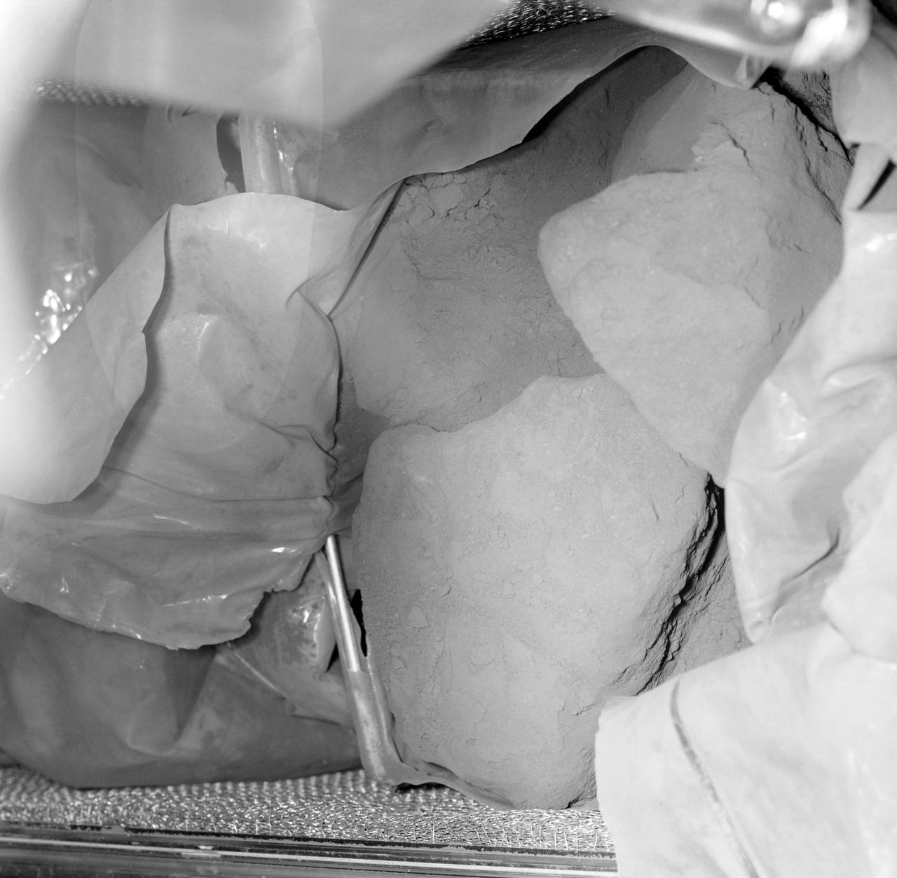 S69-60294 (26 Nov. 1969) --- One of the first views of the Apollo 12 lunar rocks is this photograph of the open sample return container. The large rock is approximately 7 1/2 inches across and is larger than any rock brought back to Earth by the crew of the Apollo 11 lunar landing mission. Two of the rocks in the first container are crystalline and generally lighter in color than those returned on the first lunar landing. The rocks in this box are medium charcoal brown/gray in color.