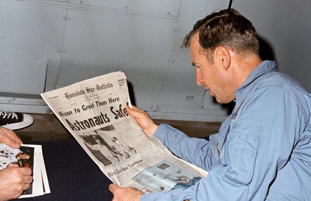 NASA image: Astronaut James Lovell reads newspaper account of Apollo 13 safe recovery