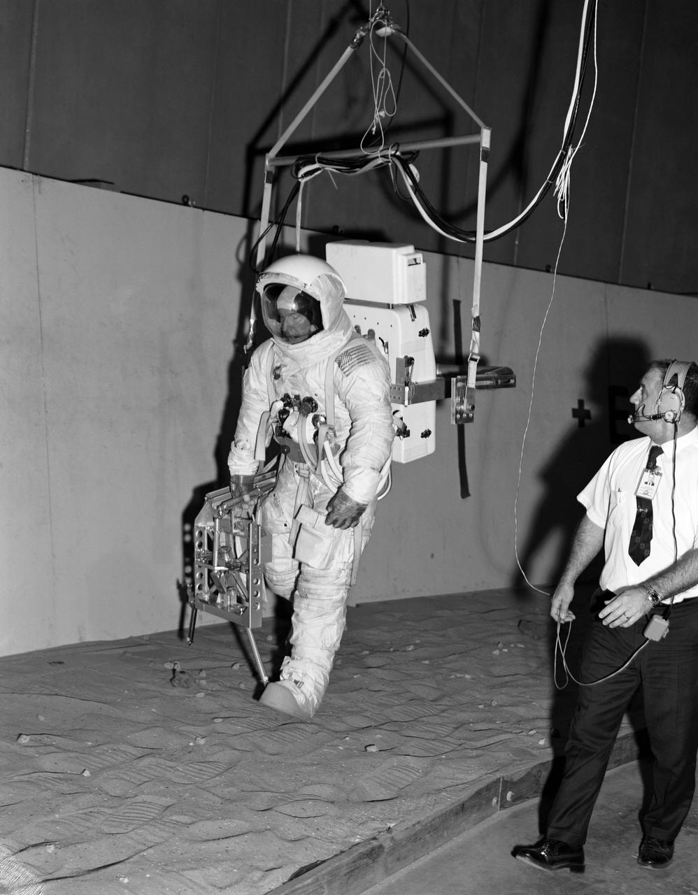 S70-28229 (16 Jan. 1970) --- Astronaut James A. Lovell Jr., commander of the Apollo 13 lunar landing mission, participates in lunar surface simulation training at the Manned Spacecraft Center.  Lovell is attached to a Six Degrees of Freedom Simulator.  He is carrying an Apollo Lunar Hand Tools carrier in his right hand.