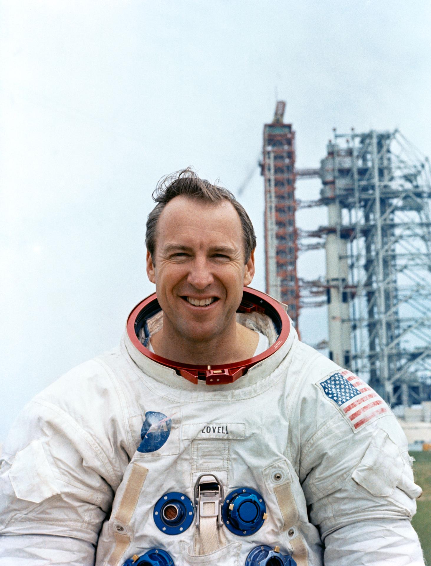 Portrait of astronaut Jim Lovell in his space suit posing in front of the Apollo 13 - Saturn V rocket.