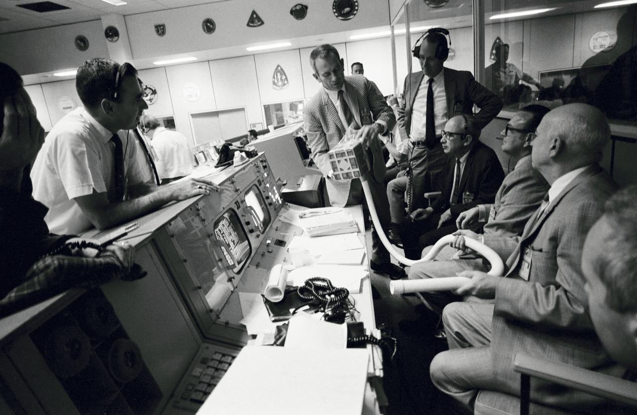 S70-35013 (15 April 1970) --- Prototype of the "mail box" constructed at the Manned Spacecraft Center (MSC) to remove carbon dioxide from the Apollo 13 Command Module (CM) is displayed in the Mission Control Center (MCC).  The "mail box" was constructed when it became apparent CO2 was prevalent in the CM and the spacecraft's lithium hydroxide system was not removing it sufficiently.  A space suit exhaust hose is connected to a lithium hydroxide canister to purge the cabin air.  There are 16 such canisters in the CM and each will last approximately 12 hours.  Looking at the "mail box" are (from the left): Milton L. Windler, shift 1 flight director; Dr. Donald K. (Deke) Slayton, director of flight crew operations, MSC; Howard W. Tindall, deputy director, flight operations, MSC; Sigurd A. Sjoberg, director, flight operations, MSC; Dr. Christopher C. Kraft, deputy director, MSC; and Dr. Robert R. Gilruth, director, MSC.