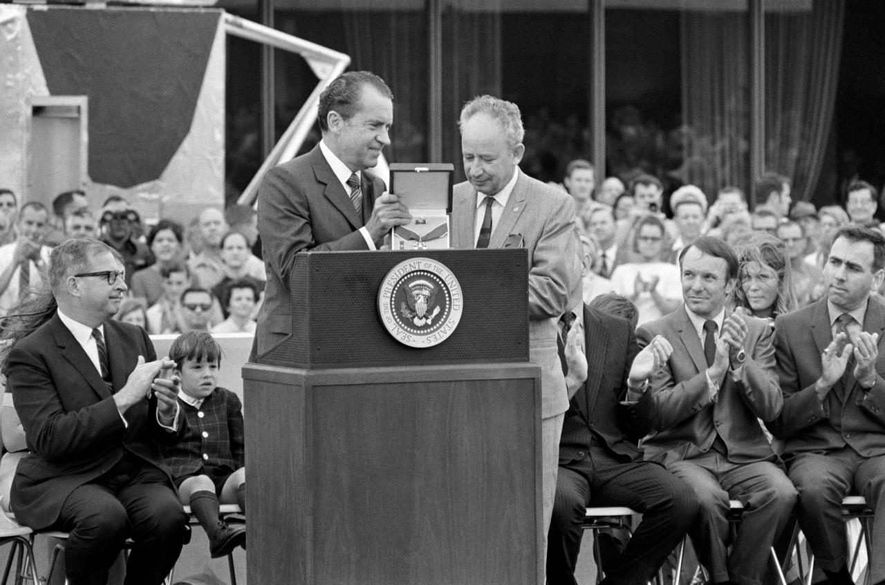 S70-35594 (18 April 1970) --- President Richard M. Nixon presents the Presidential Medal of Freedom to the Apollo 13 Mission Operations Team at Manned Spacecraft Center (MSC).  Accepting for the team is Sigurd A. Sjoberg, director of Flight Operations at MSC. Dr. Thomas O. Paine, Administrator, National Aeronautics and Space Administration (NASA), is at left. Also seen here on the speaker's platform are Jeffrey C. Lovell, son of astronaut James A. Lovell Jr., commander of the Apollo 13 mission; Gerald D. Griffin (second from right) and Milton L. Windler, two of four flight directors who worked around the clock during the mission.