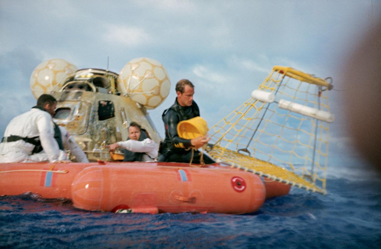 S70-35631 (17 April 1970) --- A water-level view of recovery operations for the Apollo 13 mission in the South Pacific Ocean.  The three crewmen have egressed their spacecraft, and are awaiting the readying of the "Billy Pugh" net which will hoist them to a helicopter hovering above. The crewmembers (from the left) are astronauts Fred W. Haise Jr., lunar module pilot; John L. Swigert Jr., command module pilot; (only partially visible between Haise and the Command Module (CM)), and James A. Lovell Jr., commander. A U.S. Navy underwater demolition team swimmer prepares to assist Haise into the net. Apollo 13 splashdown occurred at 12:07:44 p.m. (CST), April 17, 1970, in the South Pacific, about four miles from the USS Iwo Jima, prime recovery ship.