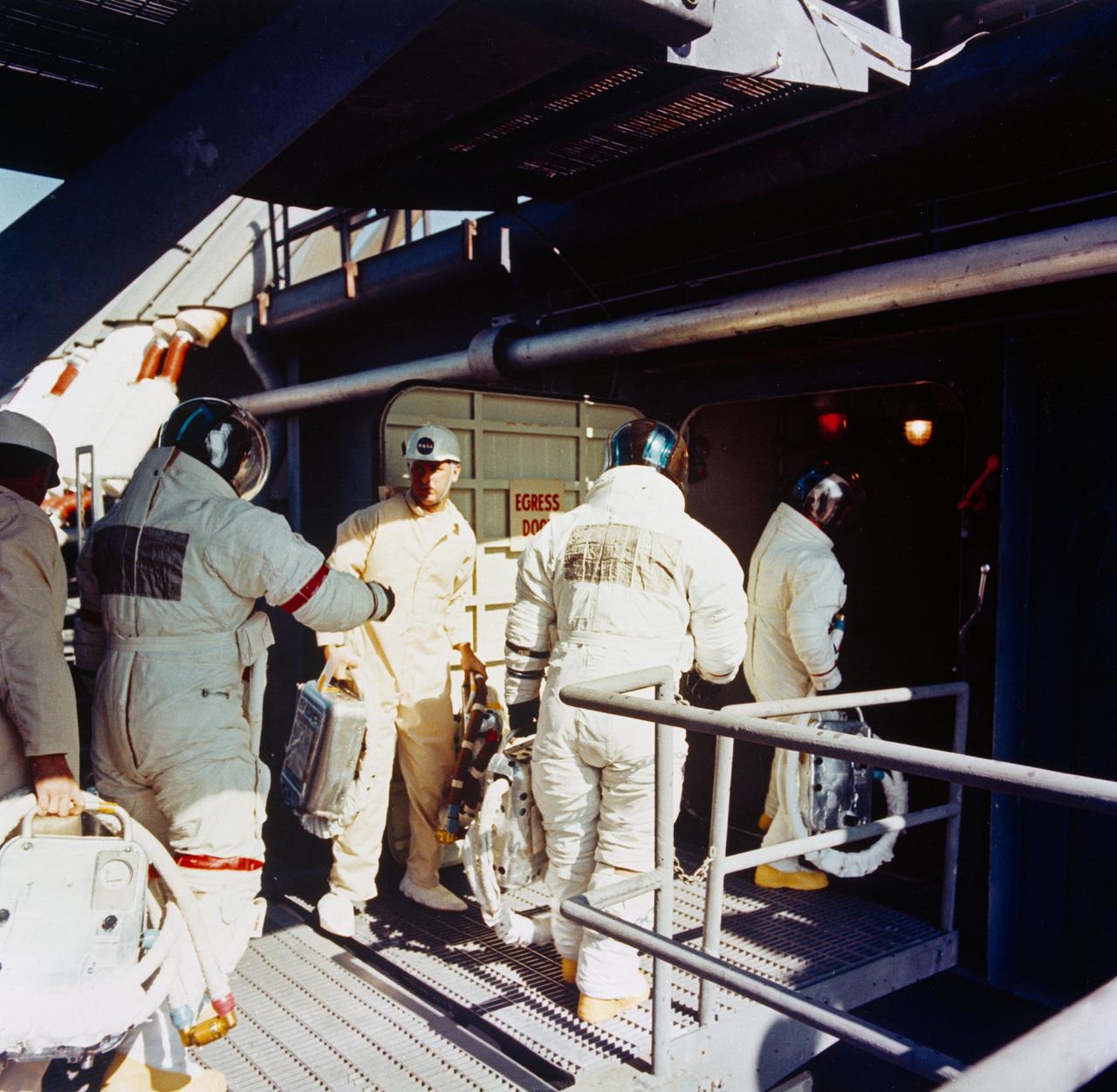 S71-16635 (31 Jan. 1971) --- The three Apollo 14 astronauts arrive at the White Room atop Pad A, Launch Complex 39, during the Apollo 14 prelaunch countdown. Apollo 14, with Alan B. Shepard Jr., commander; Stuart A. Roosa, command module pilot; and Edgar D. Mitchell, lunar module pilot, aboard was launched at 4:03:02 p.m. (EST), Jan. 31, 1971, on a lunar landing mission. Note identifying bands on the sleeve and leg of Shepard. Standing in the center foreground is astronaut Thomas P. Stafford, chief of the MSC Astronaut Office.