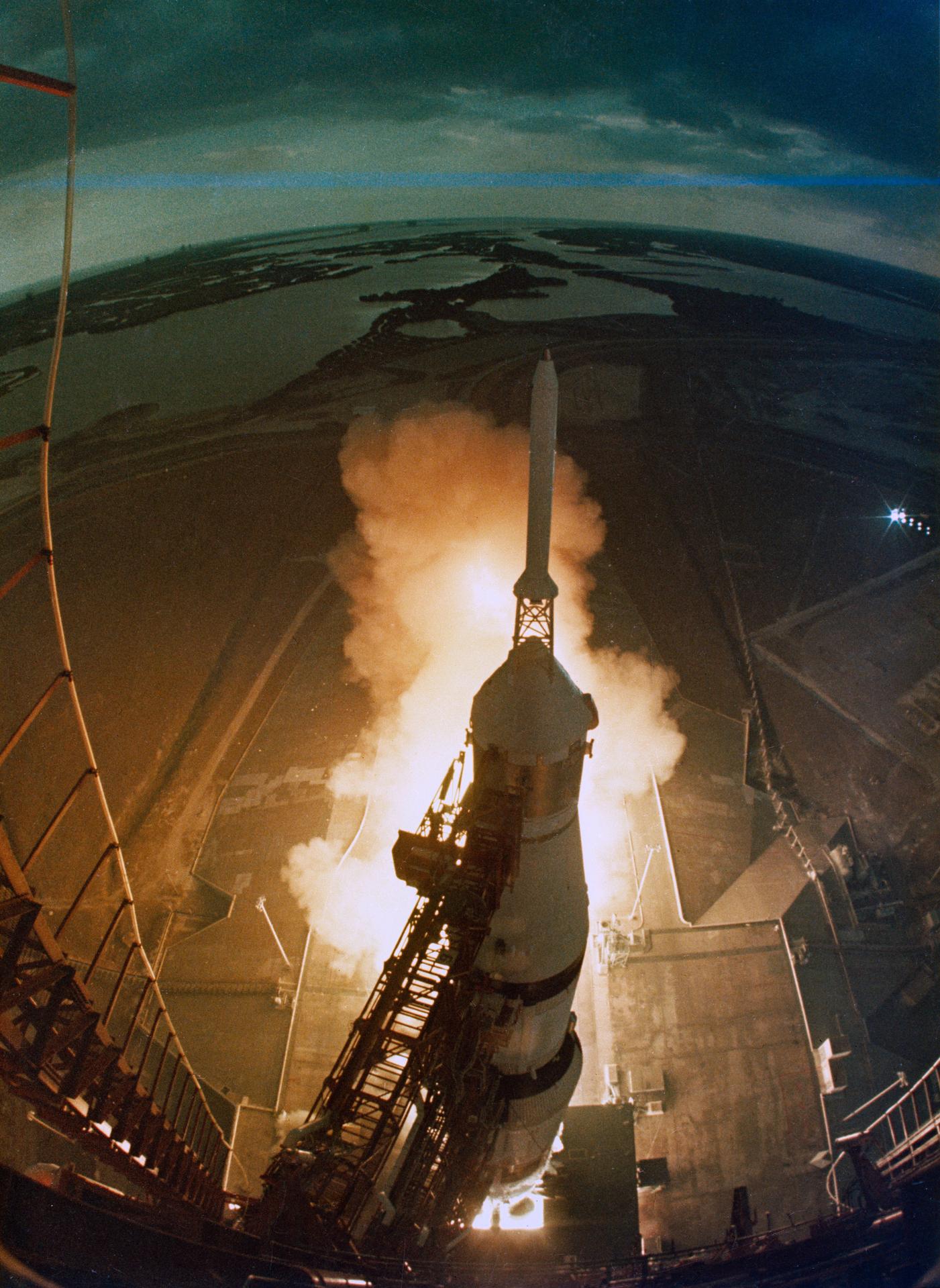 View from above of the Apollo 14 rocket beginning to lift off from the launch pad in a fiery plume of smoke