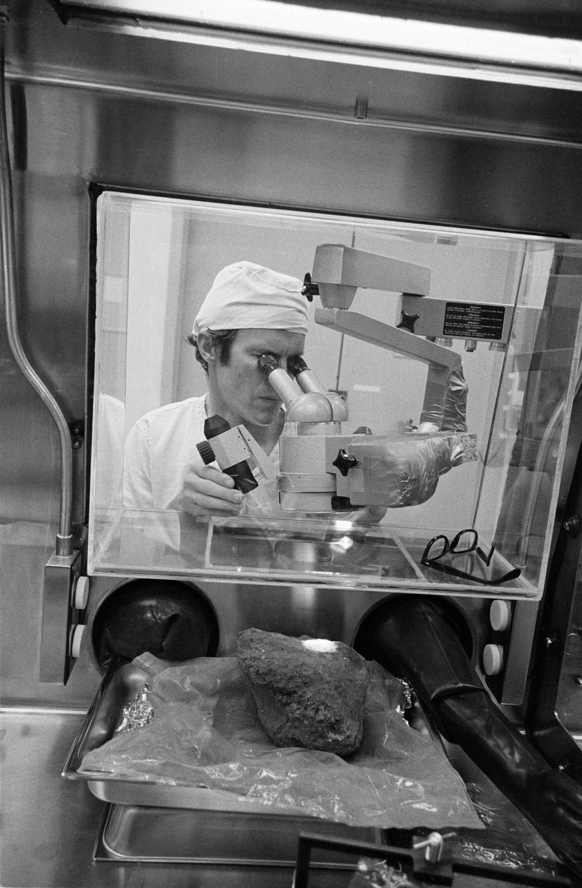 S71-21245 (24 Feb. 1971) --- Dr. Daniel H. Anderson, an aerospace technologist and test director in the Nonsterile Nitrogen Processing Laboratory in the Lunar Receiving Laboratory (LRL) at the Manned Spacecraft Center (MSC) looks at much-discussed Apollo 14 basketball-size rock through a microscope. The two moon-exploring crew men of Apollo 14 brought back 90-odd pounds of lunar sample material from their two periods of extravehicular activity (EVA) on the lunar surface in the Fra Mauro area.