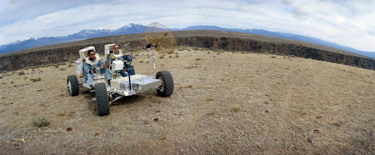 S71-23774 (11-12 March 1971) --- A wide-angle view showing two members of the prime crew of the Apollo 15 lunar landing mission riding in a Lunar Roving Vehicle trainer called "Grover" during a simulation of lunar surface extravehicular activity in the Taos, New Mexico area. They are astronauts David R. Scott (riding in left side seat), commander; and James B. Irwin, lunar module pilot. Apollo 15 will be the first mission to the moon to carry a Lunar Roving Vehicle, which will permit the astronauts to cover a larger area for exploration and sample collecting than on previous missions.