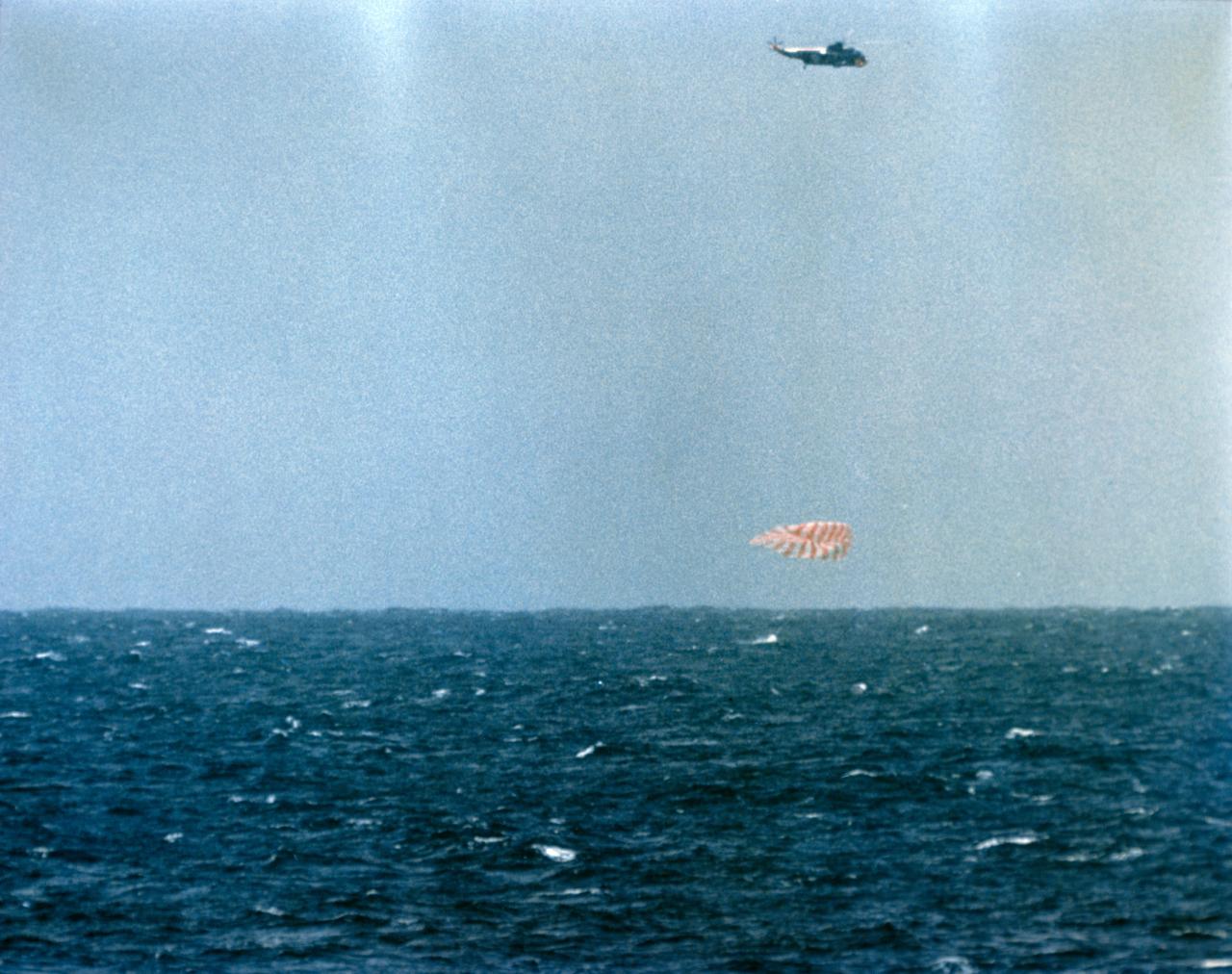 S71-24944 (16 May 1963) --- The Mercury-Atlas 9 "Faith 7" spacecraft, with astronaut L. Gordon Cooper Jr. aboard, splashes down in the Pacific Ocean to conclude a 22-orbit mission lasting 34 hours and 20.5 minutes. The capsule's parachute is fully deployed in this view. A rescue helicopter hovers overhead. Photo credit: NASA