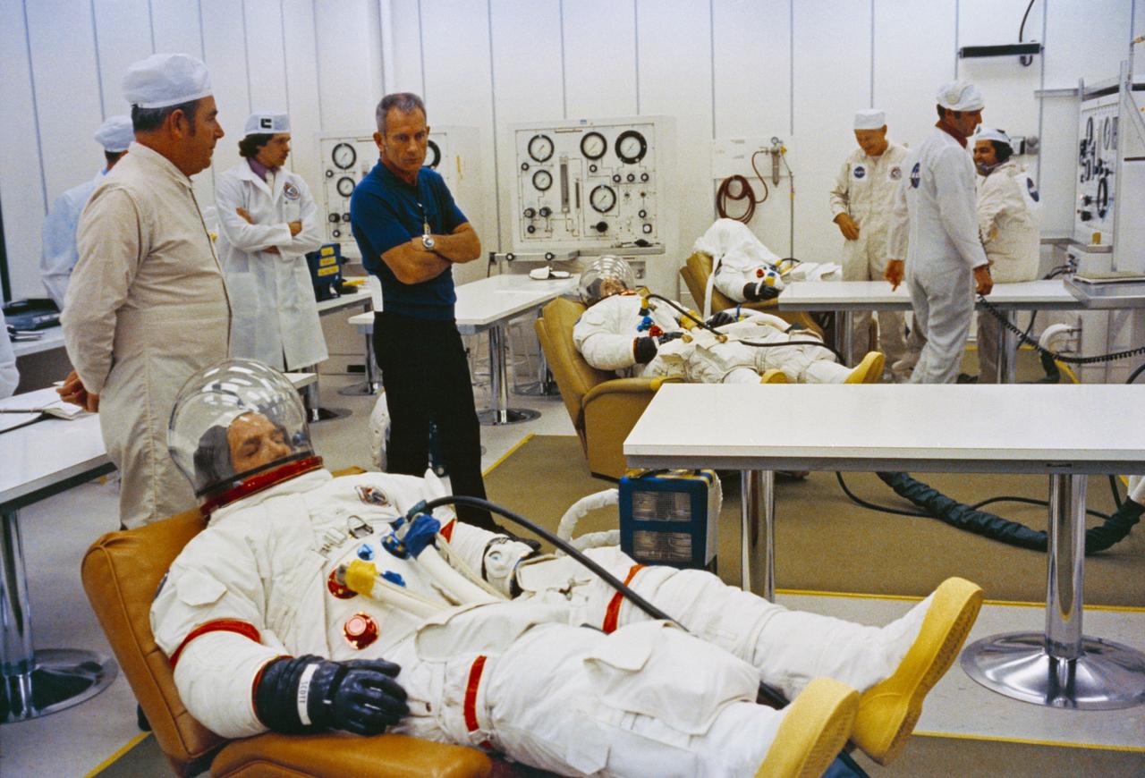 S71-41408 (26 July 1971) --- The three Apollo 15 astronauts go through suiting up operations in the Kennedy Space Center's (KSC) Manned Spacecraft Operations Building (MSOB) during the Apollo 15 prelaunch countdown. They are David R. Scott (foreground), commander; Alfred M. Worden (center), command module pilot; and James B. Irwin (background), lunar module pilot. Minutes later the crew rode a special transport van over to Pad A, Launch Complex 39, where their spacecraft awaited them. With the crew was Dr. Donald (Deke) K. Slayton (wearing dark blue sport shirt), director of Flight Crew Operations, Manned Spacecraft Center (MSC). The Apollo 15 space vehicle was launched at 9:34:00:79 a.m. (EDT), July 26, 1971, on a lunar landing mission.