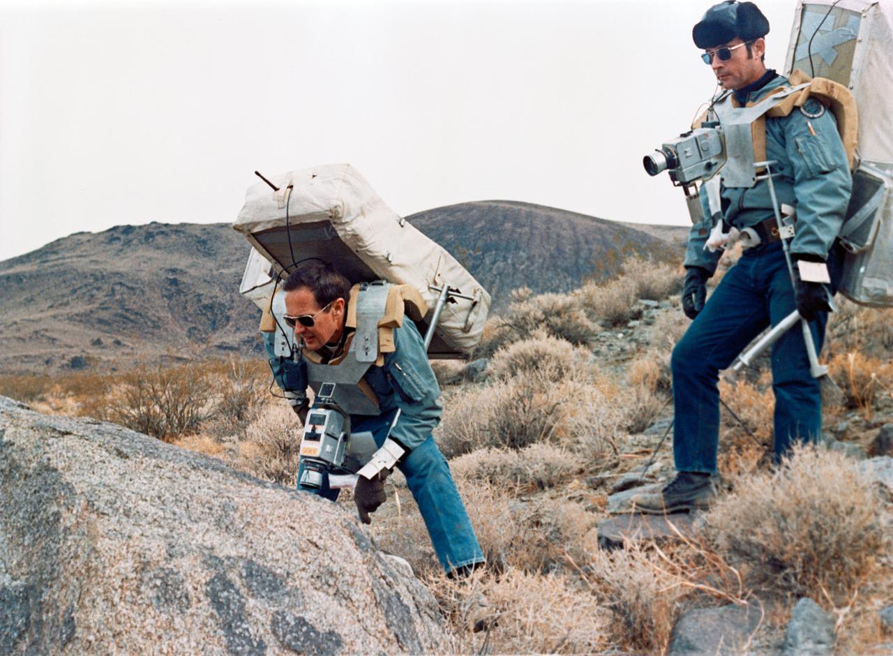S71-59355 (17-18 Nov. 1971) --- Astronauts John W. Young, right, prime crew commander for Apollo 16, and Charles M. Duke Jr., lunar module pilot, study rock formations along their simulated lunar traverse route. The prime and backup commanders and lunar module pilots for Apollo 16 took part in the two-day geology field trip and simulations in the Coso Range, near Ridgecrest, California, about 160 miles north by northeast of Los Angeles. The training and simulations were conducted Nov. 17 and 18, 1971, at the U.S. Naval Ordnance Test Station.