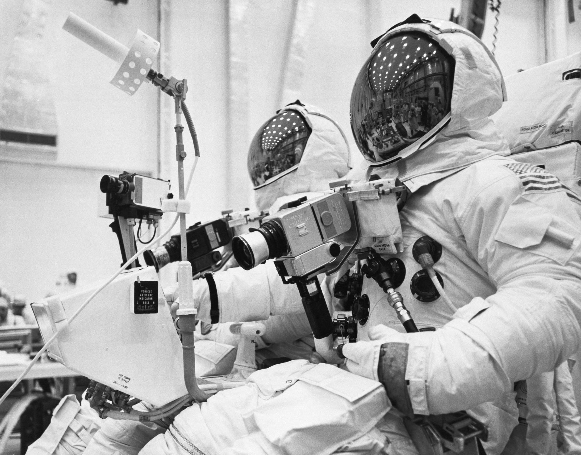 John Young and Charlie Duke are seated in the lunar rover wearing their space suits