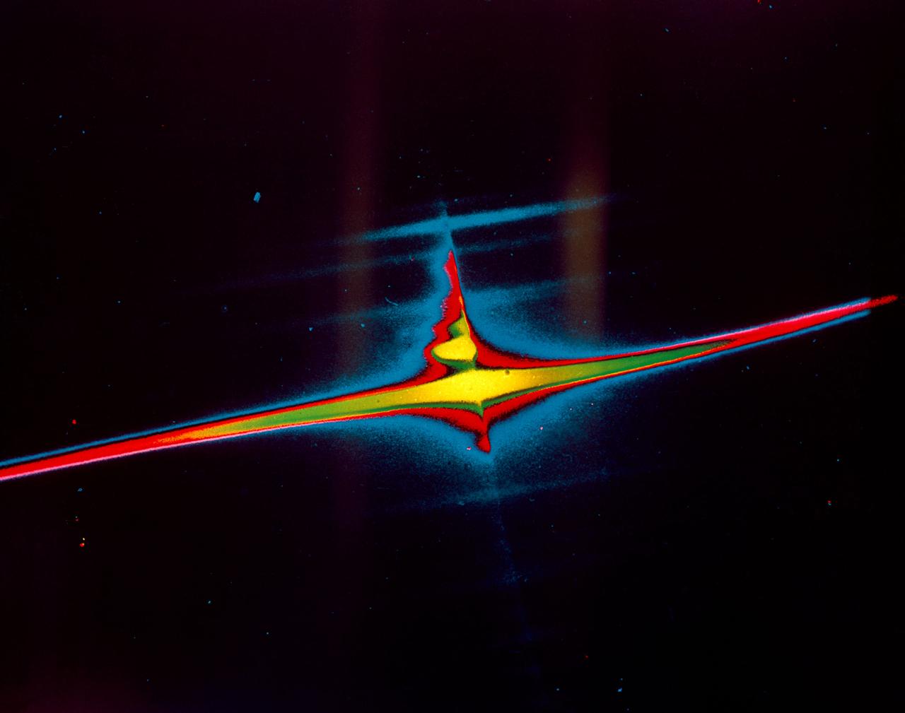 S72-40820 (21 April 1972) --- A color enhancement of a photograph taken on ultra-violet light showing the spectrum of the upper atmosphere of Earth and geocorona. The bright horizontal line is far ultra-violet emission (1216 angstrom) of hydrogen extending 10 degrees (40,000 miles) either side of Earth. The knobby vertical line shows several ultra-violet emissions from Earth's sunlit atmosphere, each "lump" being produced by one type gas (oxygen, nitrogen, helium, etc.). The spectral dispersion is about 10 angstrom per millimeter on this enlargement. The UV camera/spectrograph was operated on the lunar surface by astronaut John W. Young, commander of the Apollo 16 lunar landing mission. It was designed and built at the Naval Research Laboratory, Washington, D.C. While astronauts Young and Charles M. Duke Jr., lunar module pilot, descended in the Lunar Module (LM) "Orion" to explore the Descartes highlands region of the moon, astronaut Thomas K. Mattingly II, command module pilot, remained with the Command and Service Modules (CSM) "Casper" in lunar orbit.