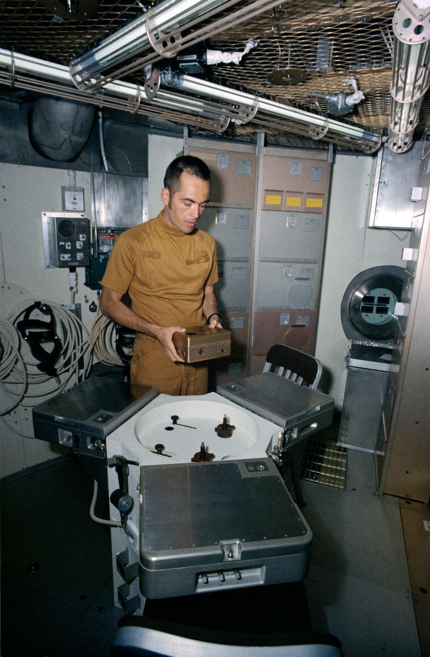 S72-43280 (15 June 1972) --- Astronaut Robert L. Crippen, Skylab Medical Experiment Altitude Test (SMEAT) commander, holds the training model of Skylab experiment T003, the aerosol analysis test, in this preview of SMEAT activity. He is part of a three-man SMEAT crew who will spend up to 56 days in the Crew Systems Division's 20-foot altitude chamber at the NASA Manned Spacecraft Center (MSC) beginning in mid-July to obtain medical data and evaluate medical experiment equipment for Skylab. The two crew members not shown in this view are astronauts Karol J. Bobko, SMEAT pilot, and Dr. William E. Thornton, SMEAT science pilot. Photo credit: NASA