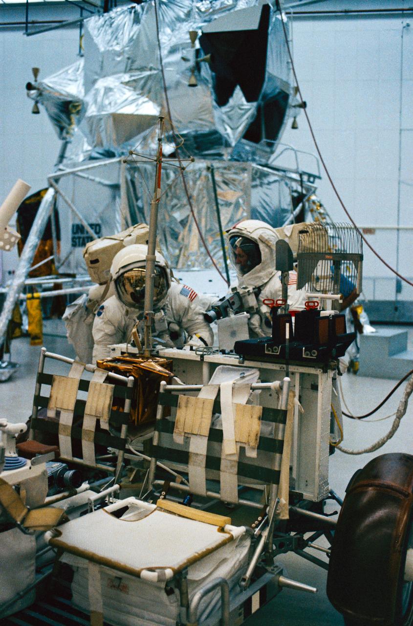 S72-48887 (September 1972) --- Astronaut Eugene A. Cernan (right), commander, and scientist-astronaut Harrison H. Schmitt, lunar module pilot, work at the aft end of a Lunar Roving Vehicle trainer during lunar surface extravehicular activity simulation training at the Kennedy Space Center (KSC), Florida. Astronauts Cernan, Schmitt, and Ronald E. Evans, command module pilot, are the prime crewmen of the Apollo 17 lunar landing mission. A Lunar Module mock-up can be seen in the background.