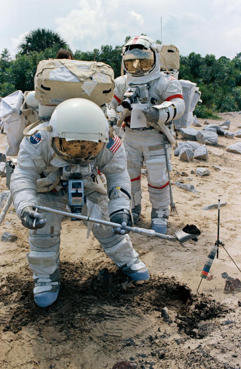 S72-48891 (September 1972) --- Two members of the prime crew of the Apollo 17 lunar landing mission participate in lunar surface extravehicular activity simulation training at the Kennedy Space Center, Florida. Scientist-astronaut Harrison H. Schmitt (foreground), lunar module pilot, simulates scooping up lunar sample material. Astronaut Eugene A. Cernan (background), commander, holds a sample bag.
