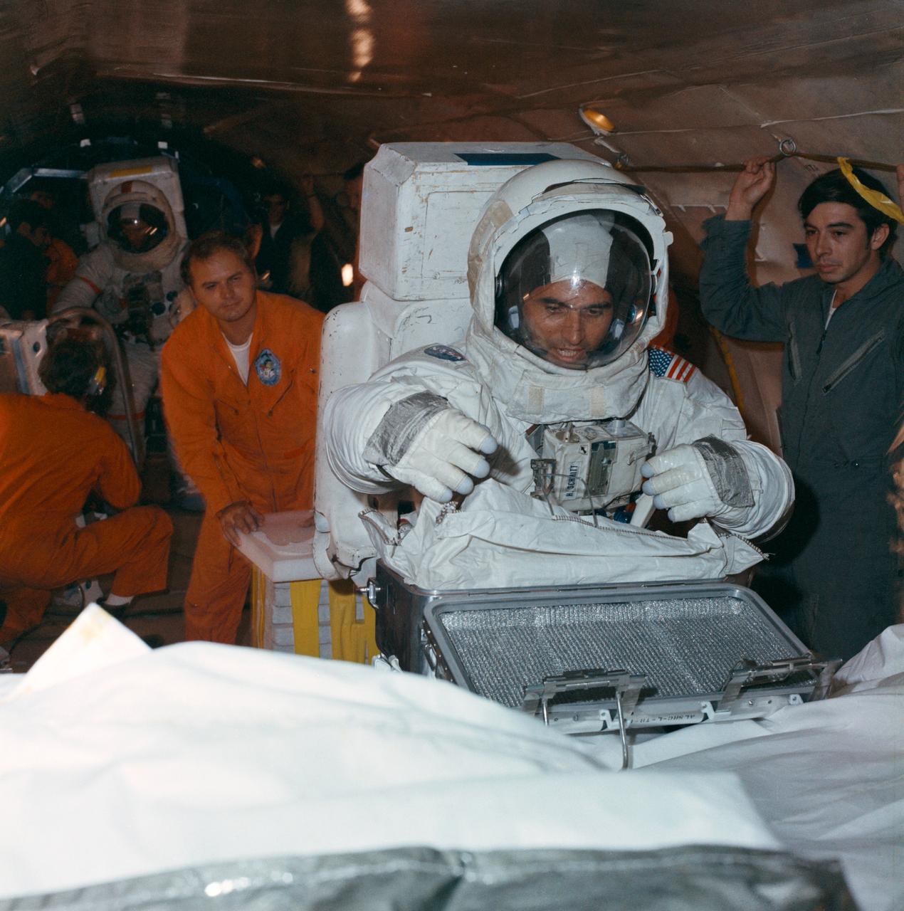 S72-50269 (September 1972) --- Scientist-astronaut Harrison H. Schmitt, lunar module pilot of the Apollo 17 lunar landing mission, seals an Apollo lunar sample return container during lunar surface extravehicular activity simulation training under one-sixth gravity conditions aboard a U.S. Air Force KC-135 aircraft. Astronaut Eugene A. Cernan, Apollo 17 commander, can be seen in the left background.