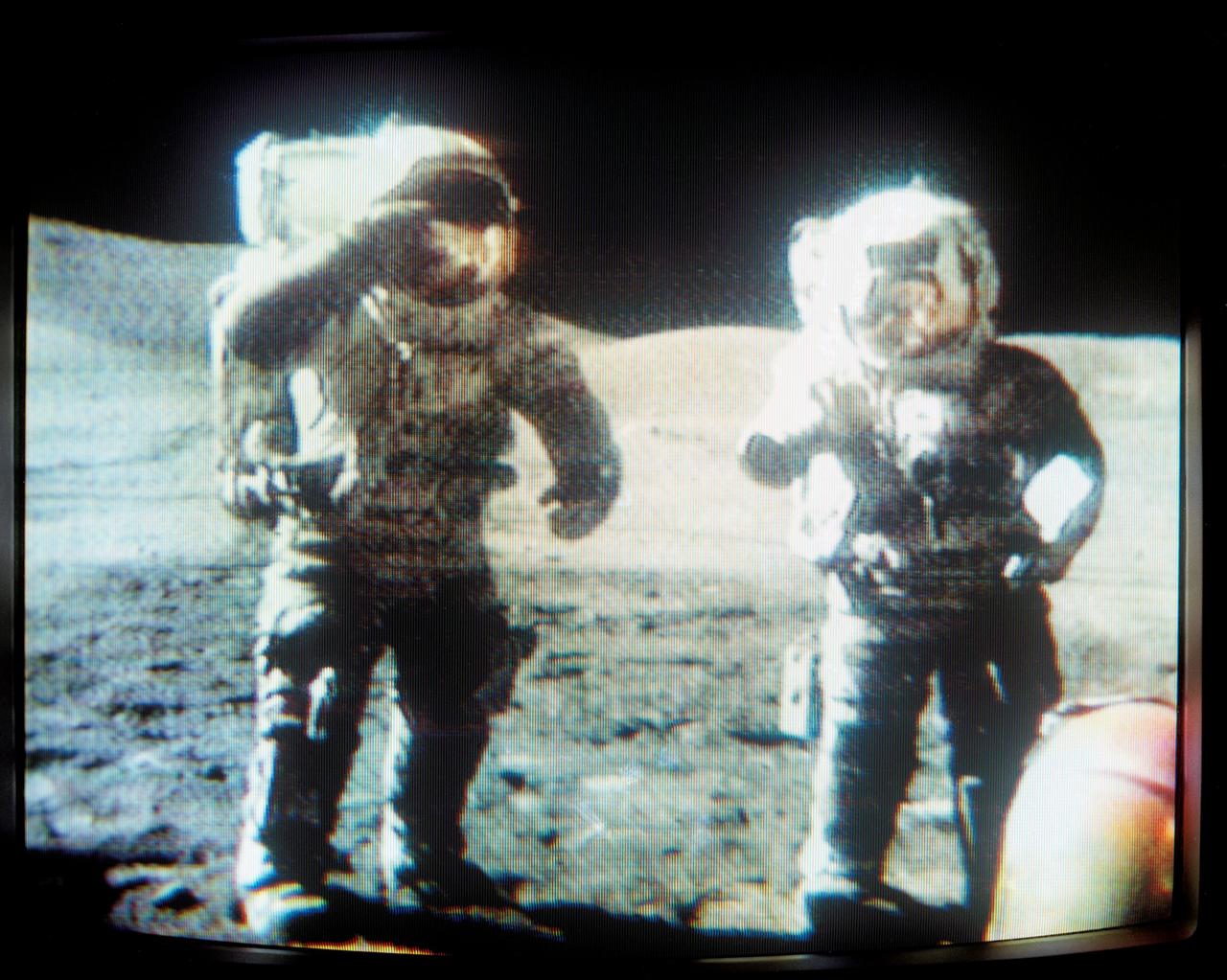 S72-55420 (13 Dec. 1972) --- Astronauts Eugene A. Cernan (on left) and Harrison H. Schmitt pay their respects and send their best wishes to the members of the International Youth Science Tour, who were visiting the Manned Spacecraft Center, in brief ceremonies near the close of the third Apollo 17 extravehicular activity (EVA) at the Taurus-Littrow landing site. This picture is a reproduction taken from a color television transmission made by the color RCA TV camera mounted on the lunar roving vehicle. Noting that they had collected a very significant rock composed of many fragments, Schmitt said, "A portion of a rock will be sent to a representative agency or museum in each of the countries represented by the young people in Houston today..." The more than 70 foreign students were in the U.S. visiting space research and science centers. In his closing remarks to the students Cernan remarked, "We salute you, promise of the future."