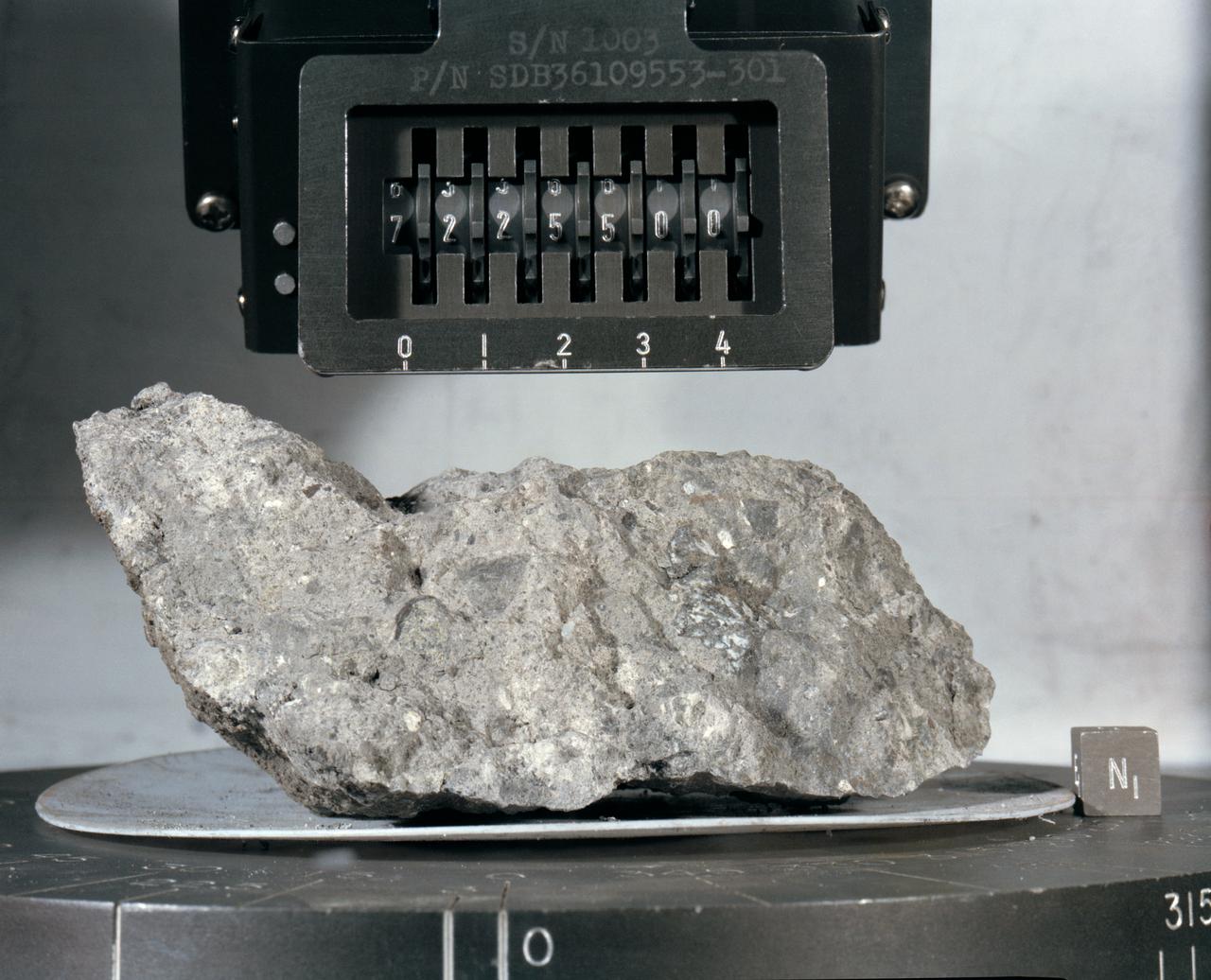 S73-16007 (December 1972) --- A "mug shot" of Apollo 17 lunar sample no. 72255 which was brought back from the lunar surface by the final team of Apollo astronauts. The rock weighs 461.2 grams and measures 2.5 x 9 x 10.5 centimeters. The light grey breccia is sub-rounded on all faces except the top and north sides.