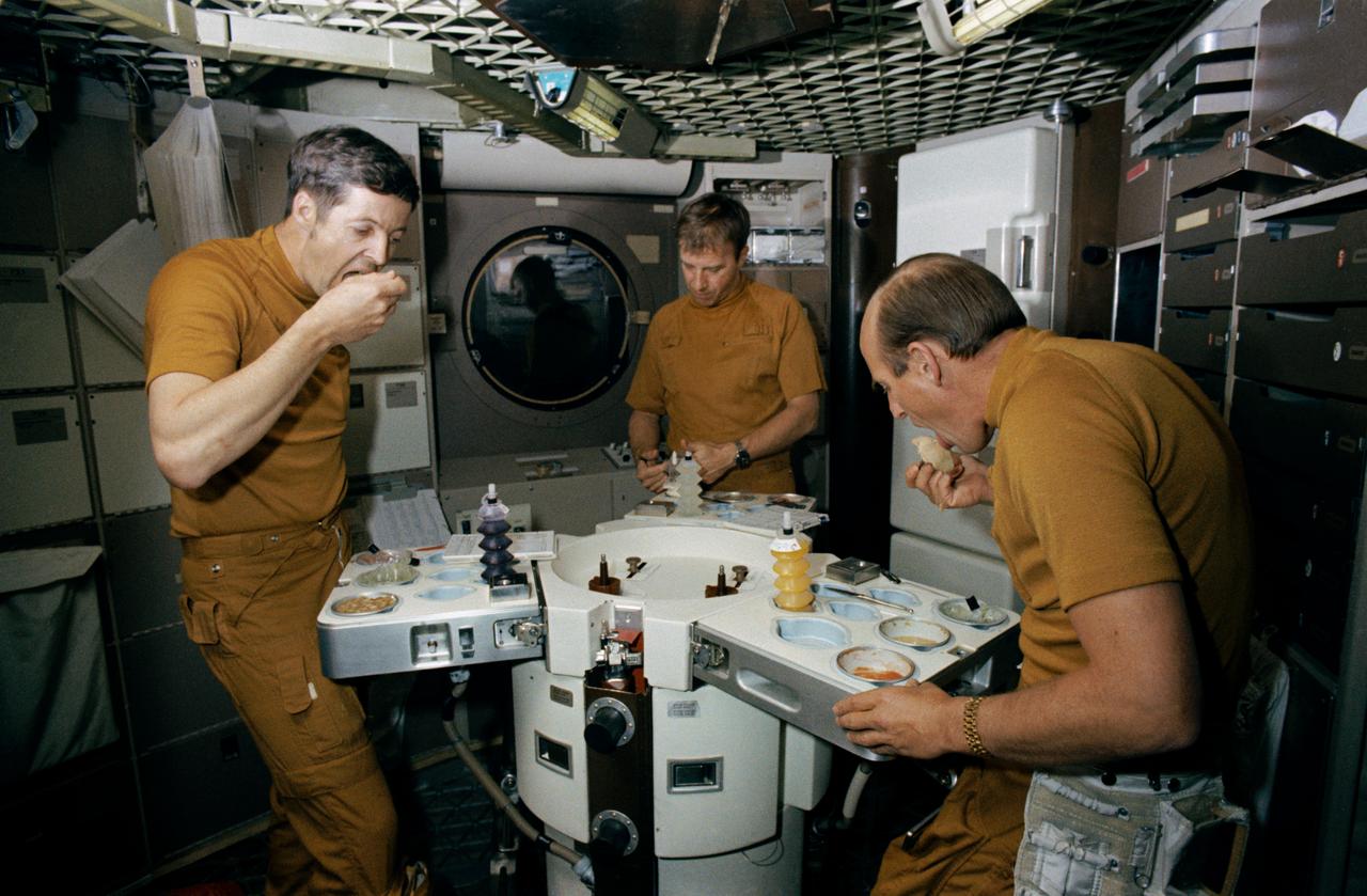 S73-20236 (1 March 1973) --- The three members of the prime crew of the first manned Skylab mission dine on specially prepared Skylab space food in the wardroom of the crew quarters of the Skylab Orbital Workshop (OWS) trainer during Skylab training at the Johnson Space Center. They are, left to right, scientist-astronaut Joseph P. Kerwin, science pilot; astronaut Paul J. Weitz, pilot; and astronaut Charles Conrad Jr., commander. Photo credit: NASA