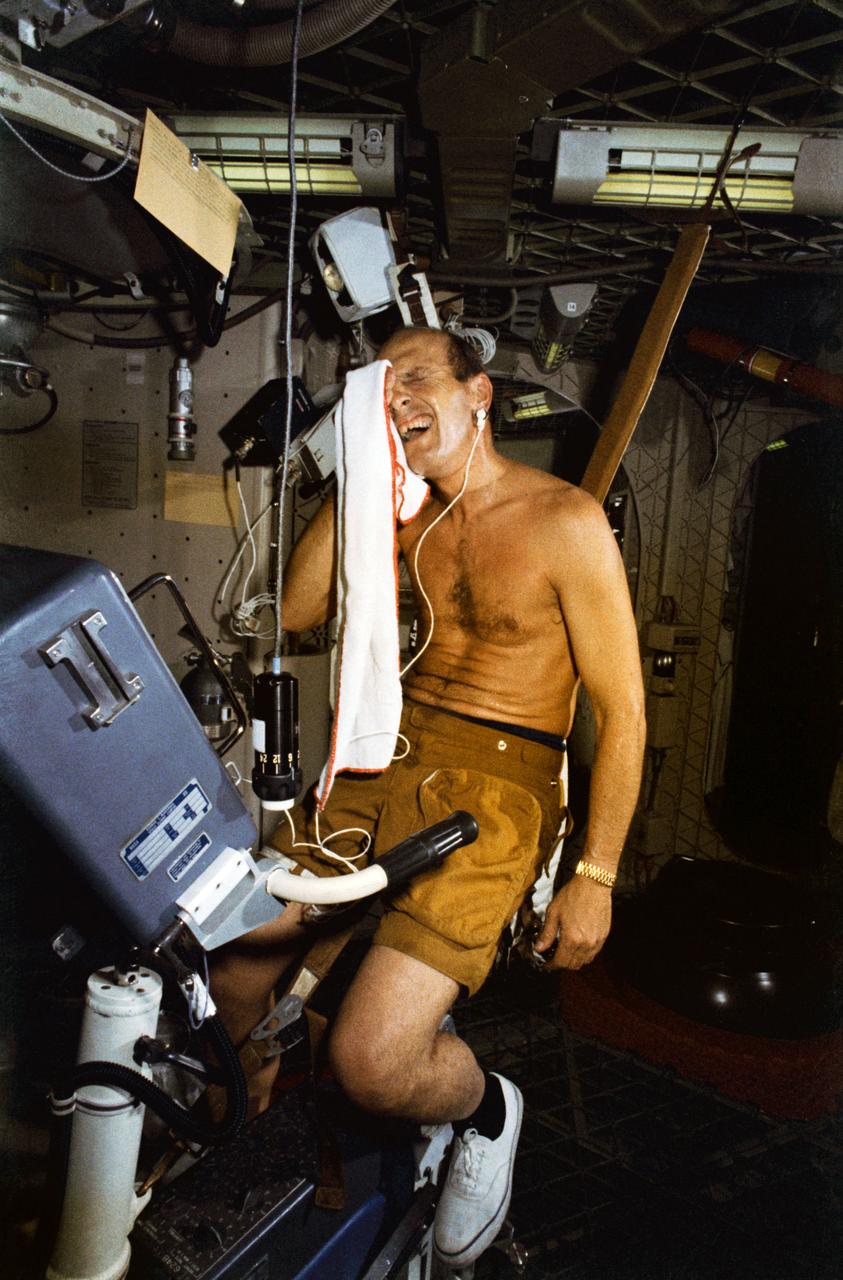 S73-20713 (1 March 1973) --- Astronaut Charles Conrad Jr., commander of the first manned Skylab mission, wipes perspiration from his face following an exercise session on the bicycle ergometer during Skylab training at Johnson Space Center. Conrad is in the work and experiments compartment of the crew quarters of the Skylab Orbital Workshop (OWS) trainer at JSC. In addition to being the prime exercise for the crewmen, the ergometer is also used for the vector-cardiogram test and the metabolic activity experiment. The bicycle ergometer produces measured workloads for use in determining man's metabolic effectiveness. Photo credit: NASA
