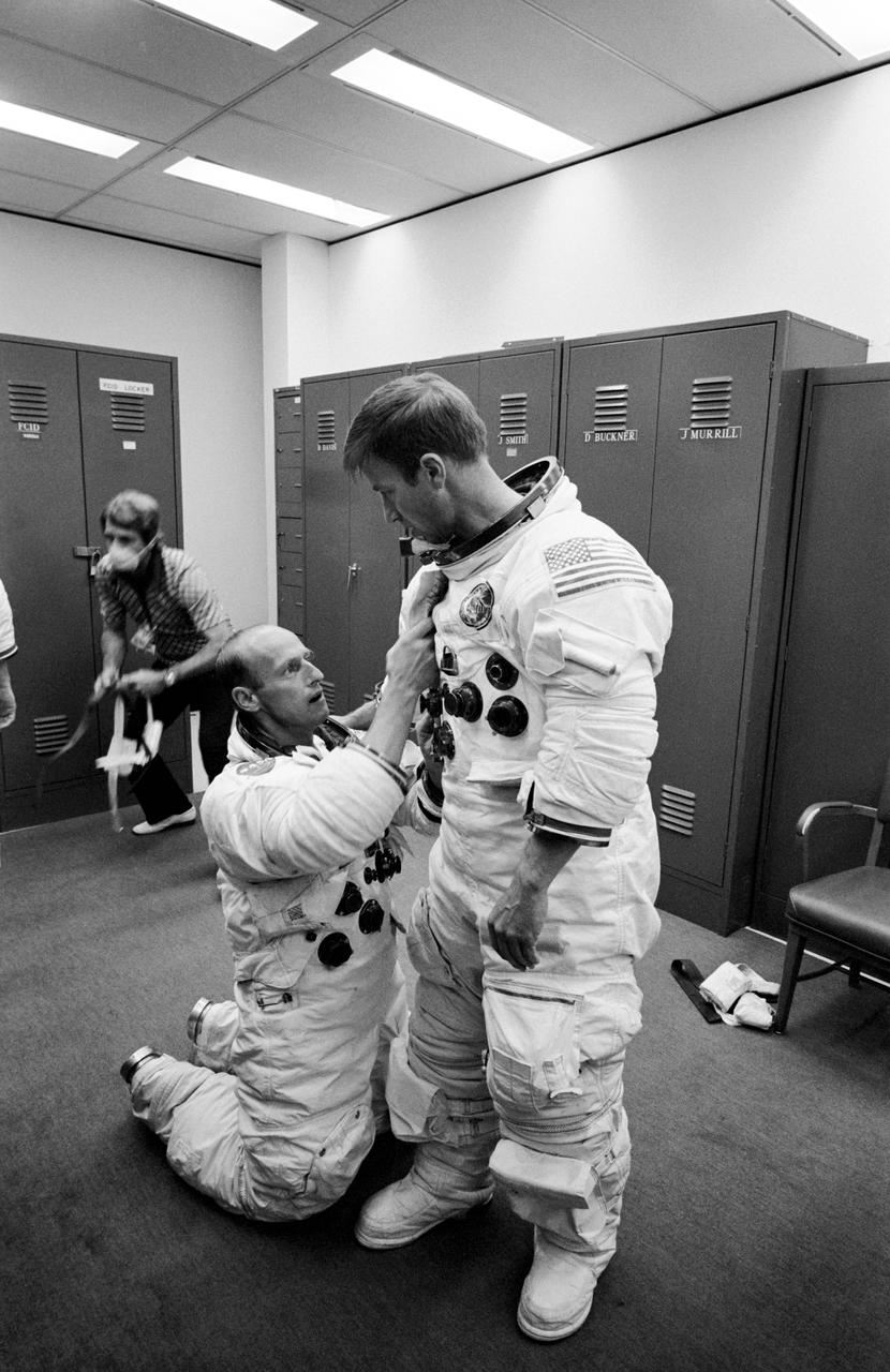 S73-25283 (8 May 1973) --- Astronaut Paul J. Weitz, prime crew pilot of the first manned Skylab mission, is suited up in Bldg. 5 at Johnson Space Center during prelaunch training activity. He is assisted by astronaut Charles Conrad Jr., prime crew commander. The man in the left background is wearing a face mask to insure that Conrad, Joseph Kerwin and Weitz are not exposed to disease prior to launch. Photo credit: NASA