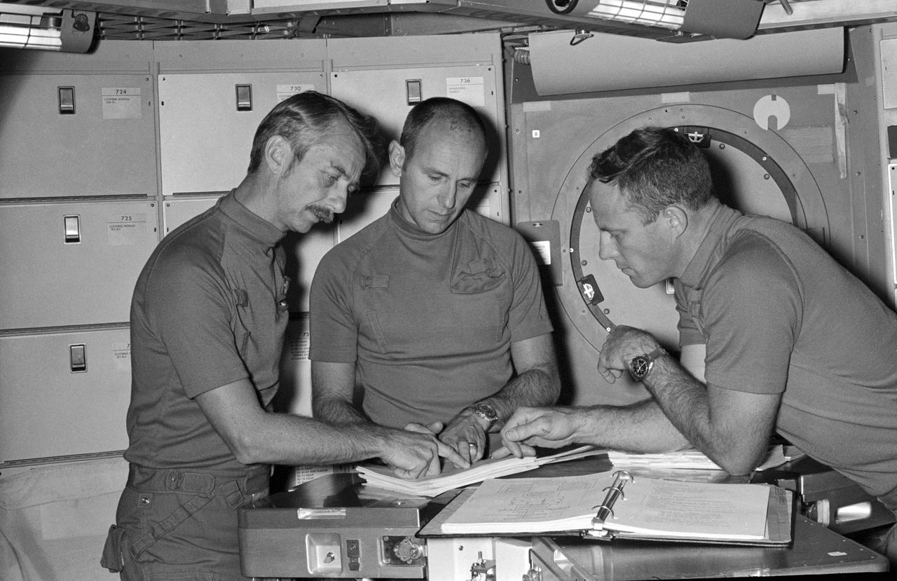 S73-28419 (16 June 1973) --- The three prime crewmen of the Skylab 3 mission check over flight data during a training session in the crew quarters of the Orbital Workshop (OWS) trainer in the Mission Simulation and Training Facility at the Johnson Space Center (JSC).  They are, from left to right, scientist-astronaut Owen K. Garriott, science pilot; and astronauts Alan L. Bean, commander, and Jack R. Lousma, pilot. The 56-day, second manned Skylab Earth-orbital mission is scheduled for liftoff in the latter part of July 1973. Photo credit: NASA
