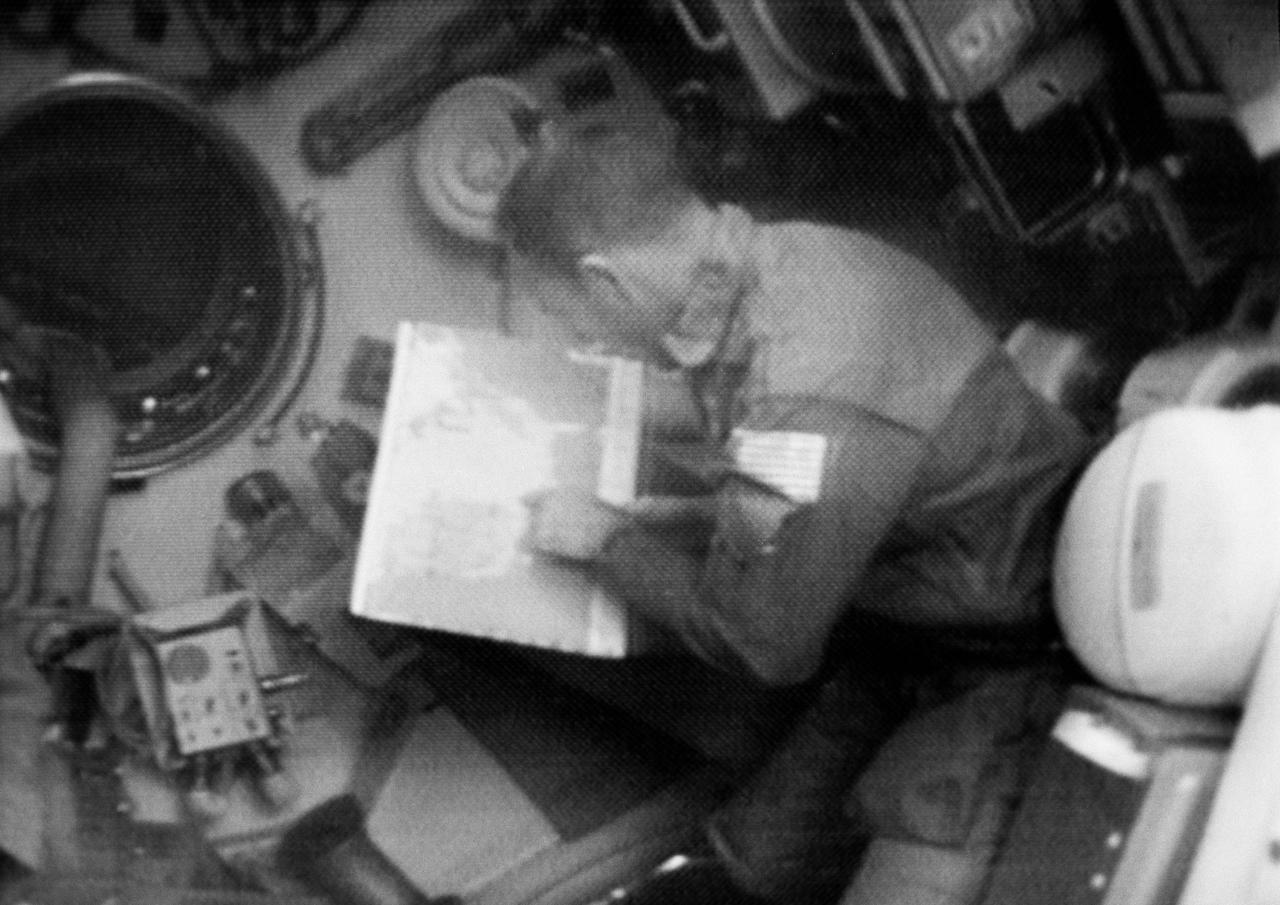 S73-31845 (3 Aug. 1973) --- Astronaut Jack R. Lousma, Skylab 3 pilot, studies a map of the U.S. during a Skylab EREP pass across the United States, as seen in this photographic reproduction taken from a television transmission made by a color TV camera aboard the Skylab space station in Earth orbit. EREP is an acronym for Earth Resources Experiments Package. Photo credit: NASA