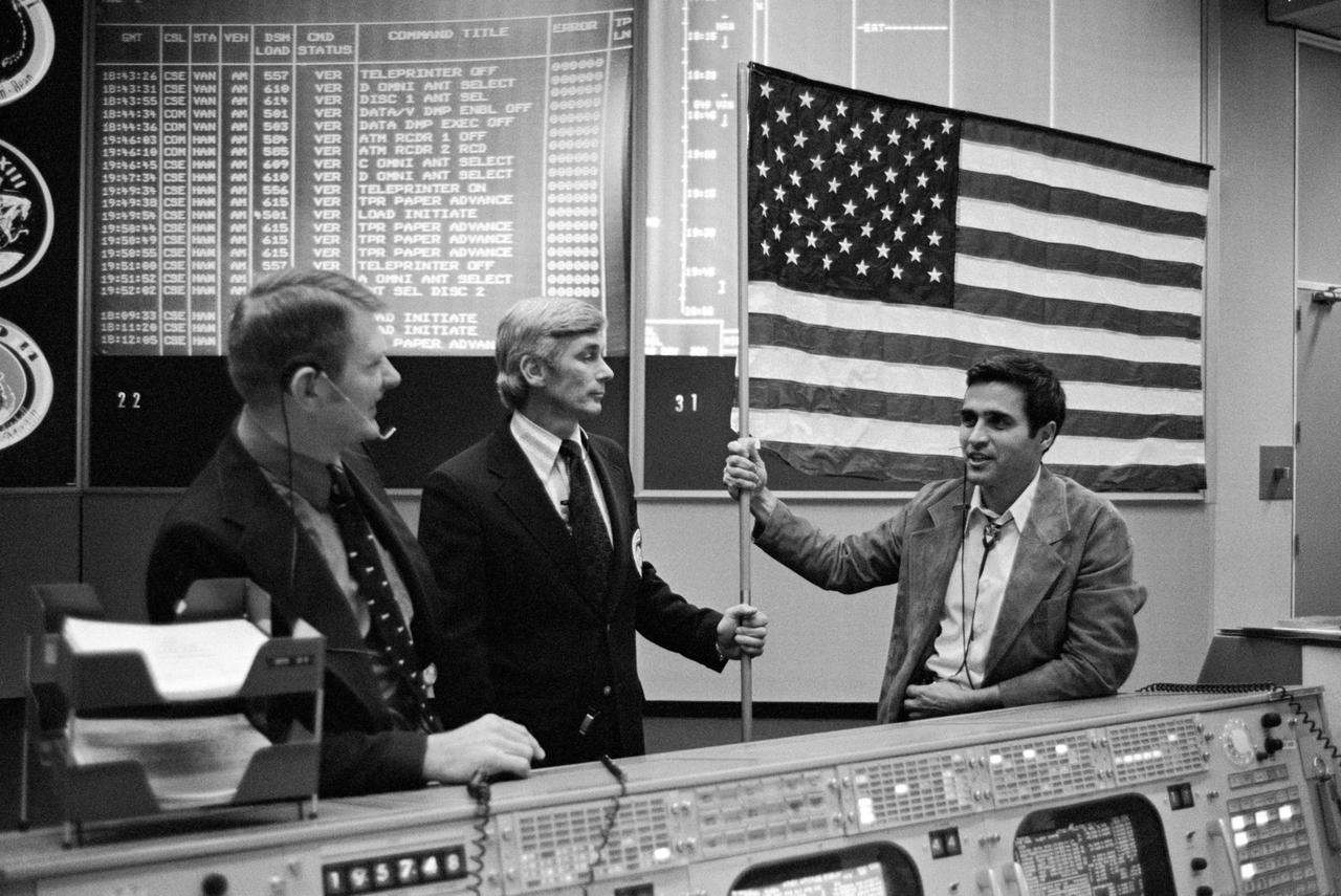 S73-38346 (11 Dec. 1973) --- Two of the three Apollo 17 crewmen join in commemoration of their historical lunar landing mission of one year ago by presenting to flight controllers in Mission Control Center (MCC) the U.S. flag which flew with them to the moon. Astronauts Eugene A. Cernan, center, Apollo 17 commander, and Harrison H. Schmitt, right, lunar module pilot, are shown with Eugene F. Kranz, who accepted the flag on behalf of all the flight controllers during special ceremonies in the Mission Operations Control Room (MOCR) of MCC during the third manned Skylab mission. Kranz is chief of the Flight Control Division of the Flight Operations Directorate at JSC.