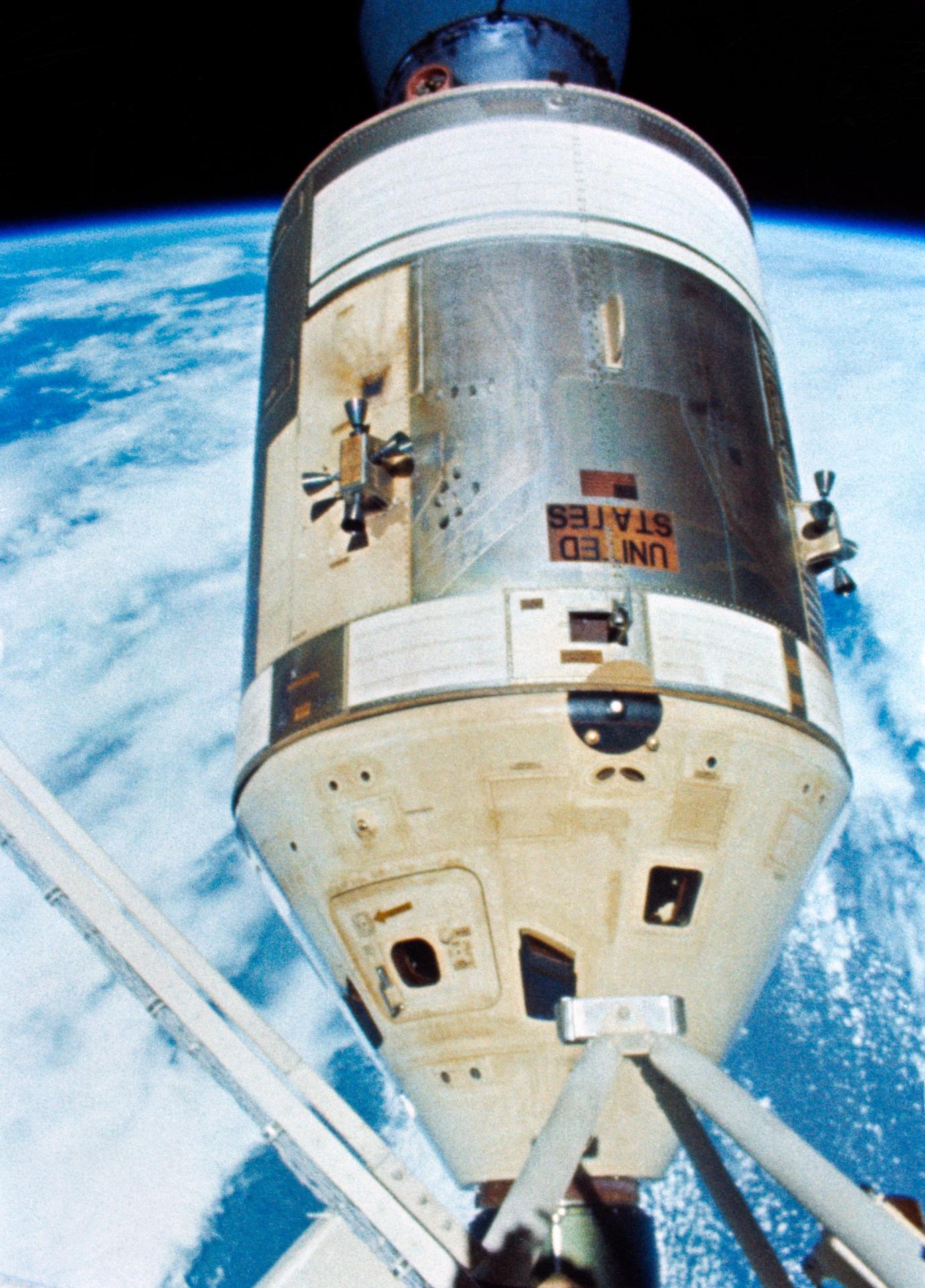 View of the Skylab 4 Command and Service Module docked to the Skylab space station. The Earth is visible in the background.