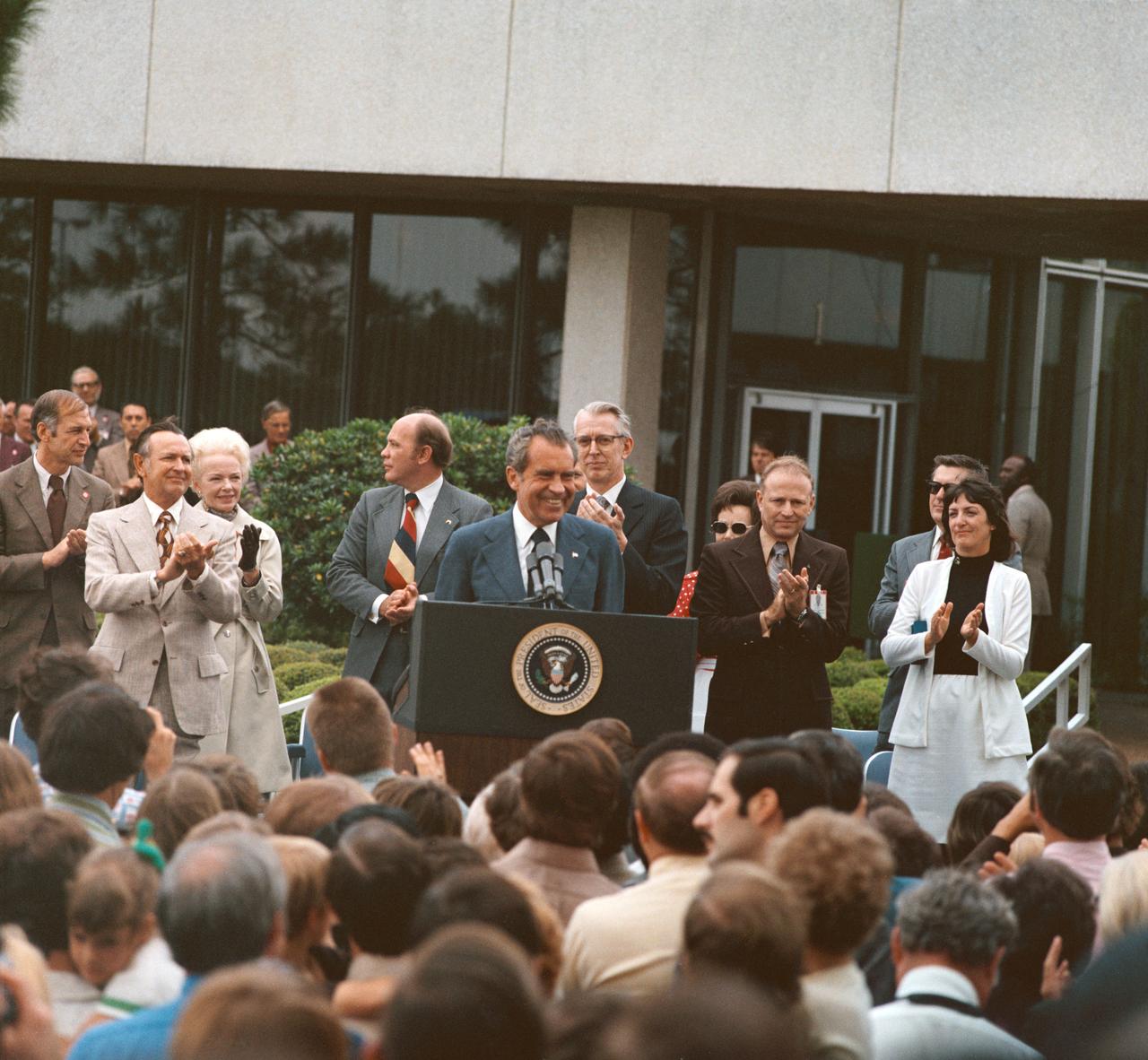 Five (5) views of President Richard M. Nixon during his visit to the JSC.  These views show the President as he addresses a crowd of employees and visitors outside of Building 1 Auditorium.  Dr. Christopher C. Kraft, Fletcher, and Astronaut Gerald Carr, with Pete Clements, George Abbey, and Jack Waite in the background is also seen with the President.           1. Pres. Richard M. Nixon           2. Dr. Christopher C. Kraft                JSC, HOUSTON, TX