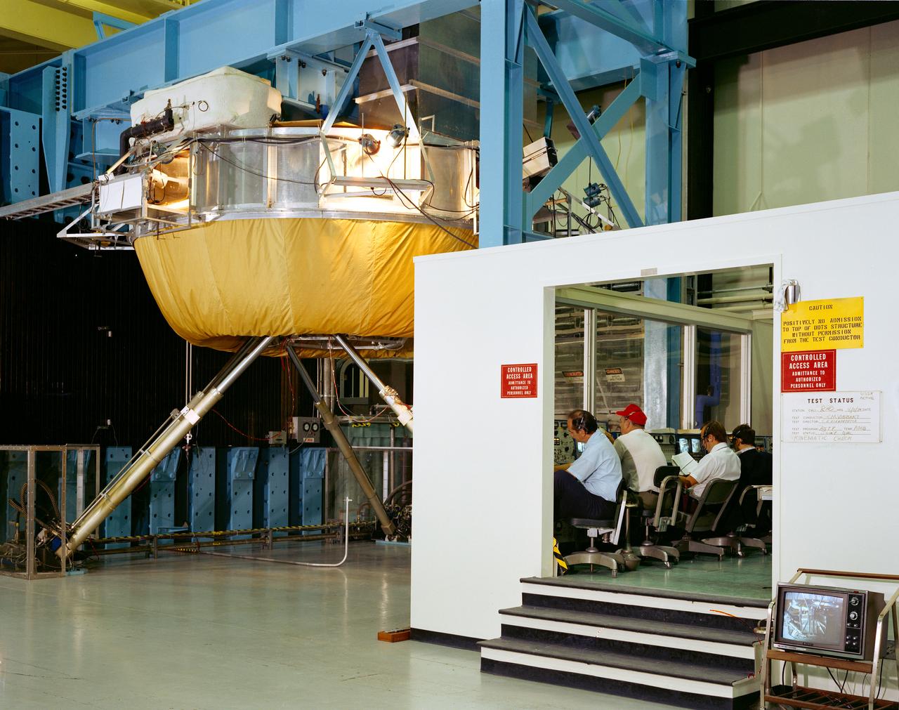 S74-27049 (4 Aug. 1974) --- Overall view of test set-up in Building 23 at the Johnson Space Center during testing of the docking mechanisms for the joint U.S.-USSR Apollo-Soyuz Test Project. The cinematic check was being made when this picture was taken. The test control room is on the right. The Soviet-developed docking system is atop the USA-NASA developed docking system. Both American and Soviet engineers can be seen taking part in the docking testing. The ASTP docking mission in Earth orbit is scheduled for July 1975.