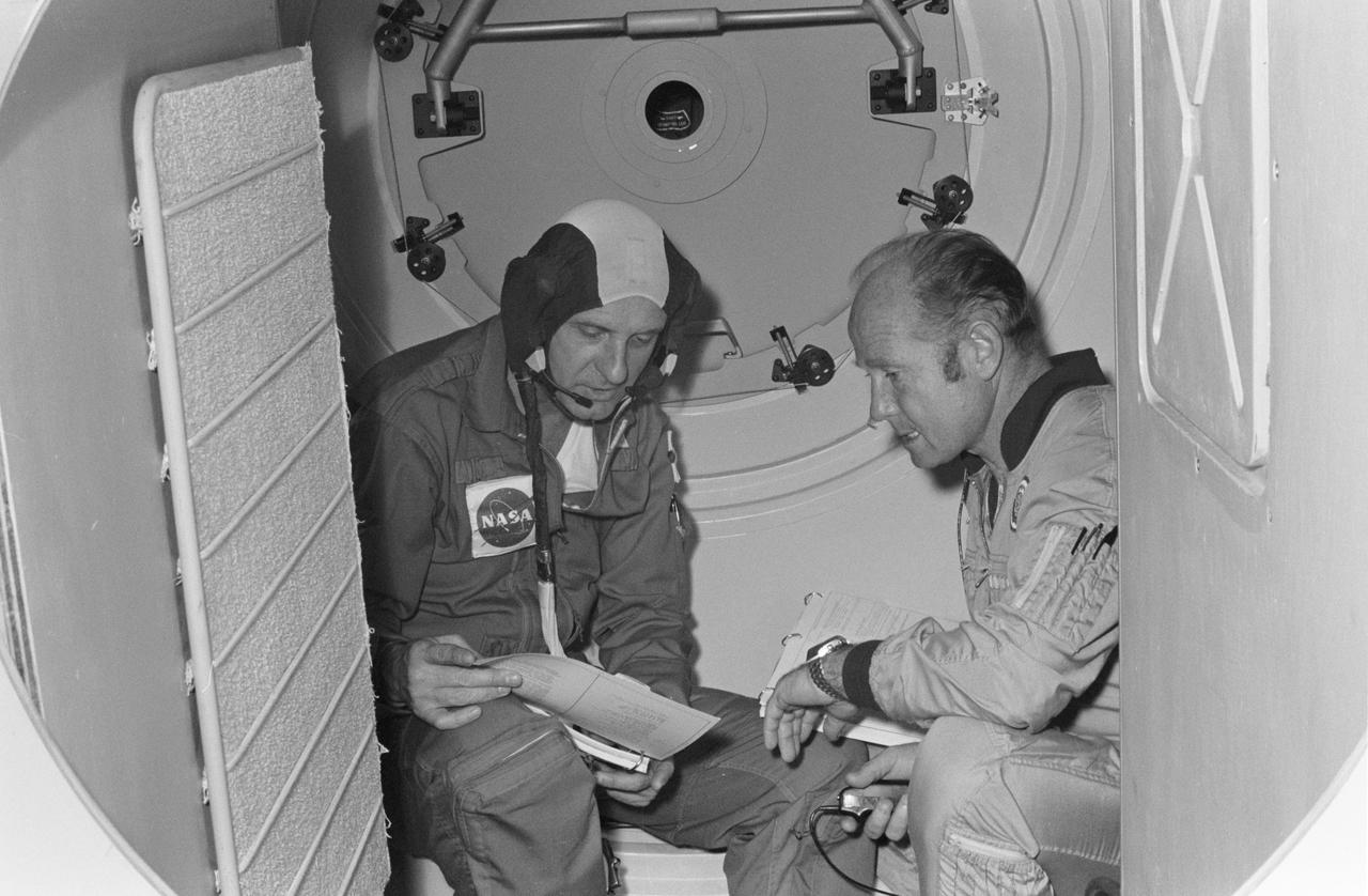 S74-29041 (September 1974) --- The commanders of the American astronaut and Soviet cosmonaut crews for the joint U.S.?USSR Apollo-Soyuz Test Project mission compare notes in a Soyuz spacecraft?s orbital module mock-up in Building 35 at the Johnson Space Center during a training and simulation exercise. They are Aleksey A. Leonov, right, and Thomas P. Stafford. The hatchway in the background leads to the Docking Module. The prime crewmen, along with backup crewmen, are training in both the U.S. and USSR for the joint mission scheduled for the summer of 1975.