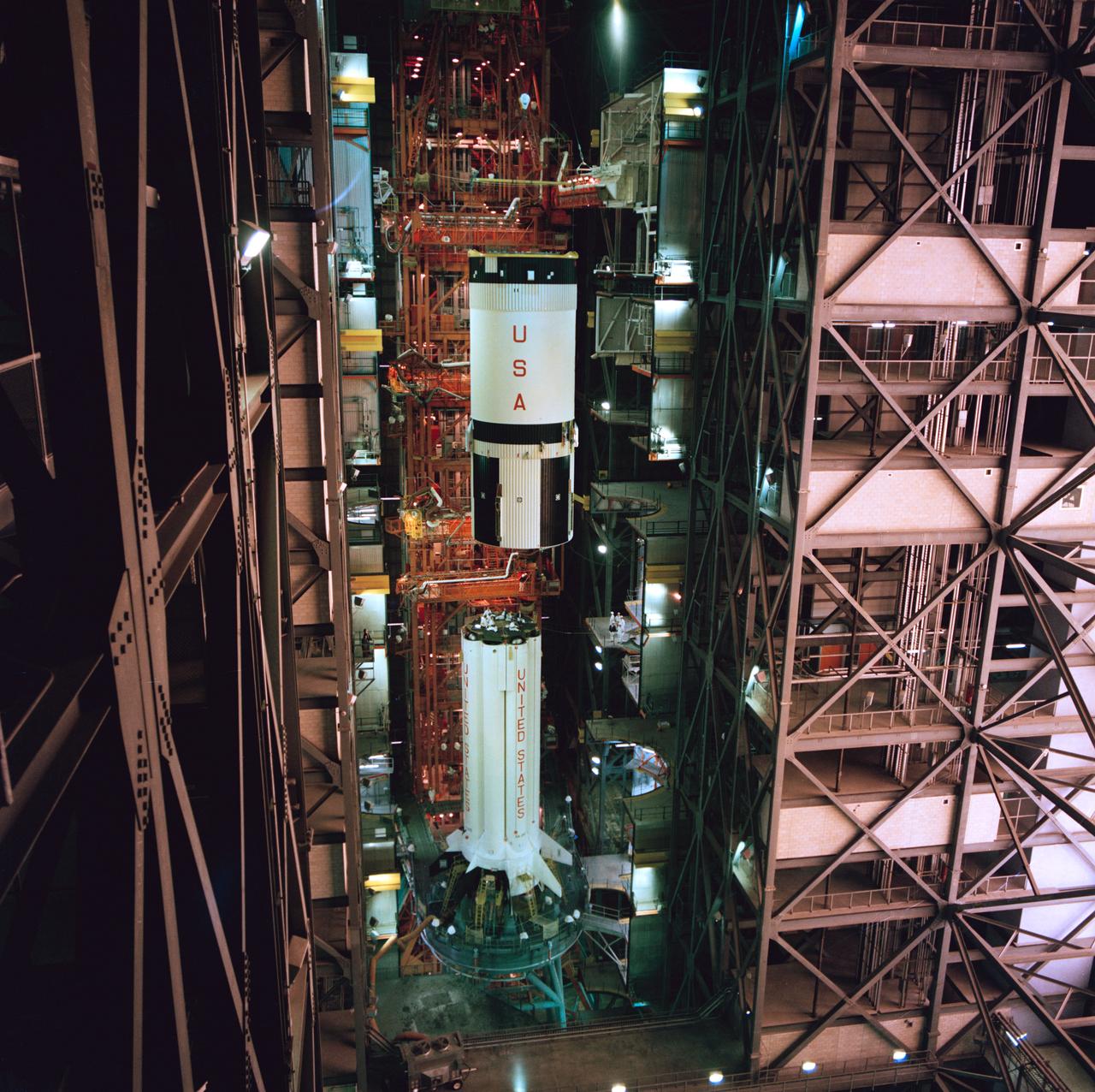 S75-20909 (January 1975) --- A high-angle view of the high-bay area in the Vehicle Assembly Building at the Kennedy Space Center showing the second (S-IVB) stage of the Saturn 1-B launch vehicle for the joint U.S.-USSR Apollo-Soyuz Test Project mission being hoisted into position for mating atop the first (S-1B) stage.  The major components of the American ASTP space vehicle will be the S-1B stage, the S-IVB stage, and a payload consisting of a Command/Service Module and a Docking Module.