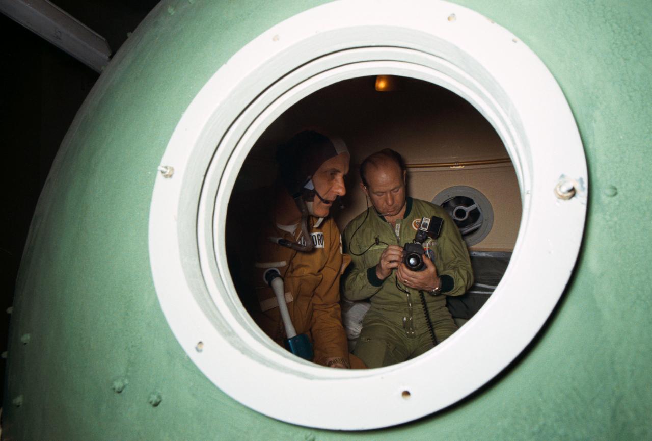 S75-21892 (20 Feb. 1975) --- Astronaut Thomas P. Stafford (left) and cosmonaut Aleksey A. Leonov participate in Apollo-Soyuz Test Project joint crew training in Building 35 at NASA's Johnson Space Center. Stafford and Leonov are the commanders of their respective prime crews. They are in the Soviet Soyuz Orbital Module mock-up. This picture was taken during a ?walk-through? of the second day?s activities in Earth orbit.