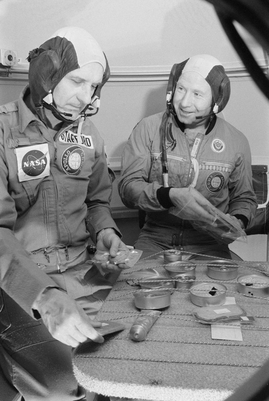 S75-22187 (25 Feb. 1975) --- Two ASTP crewmen look over food cans and packages in the Soyuz orbital module trainer in Building 35 during Apollo-Soyuz Test Project joint crew training at NASA's Johnson Space Center. They are astronaut Thomas P. Stafford (left), commander of the American ASTP prime crew; and cosmonaut Aleksey A. Leonov, commander of the Soviet ASTP first (prime) crew. The training session simulated activity on the second day in Earth orbit.
