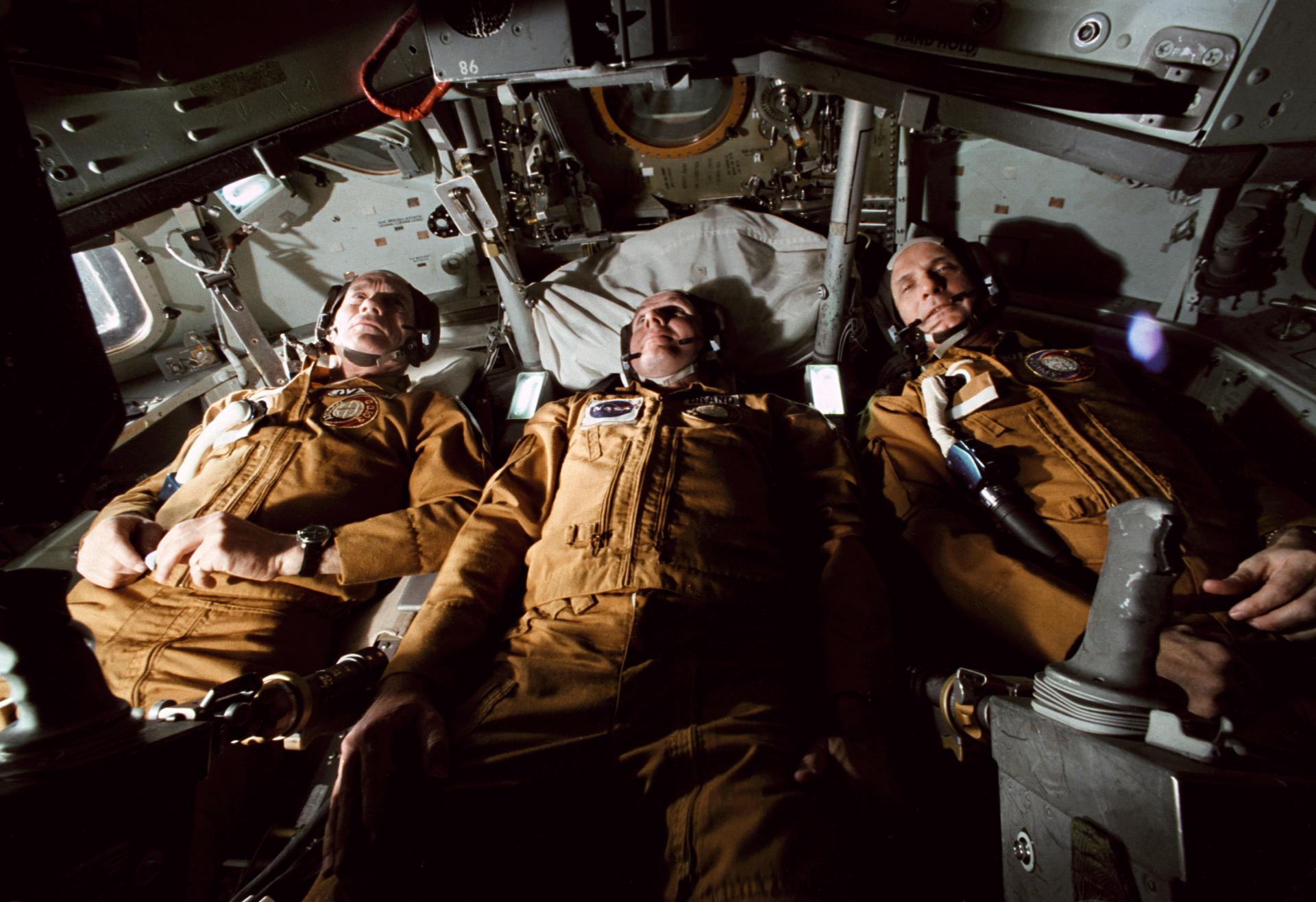 Deke Slayton, Vance Brand, and Tom Stafford sit in the Apollo Command Module trainer
