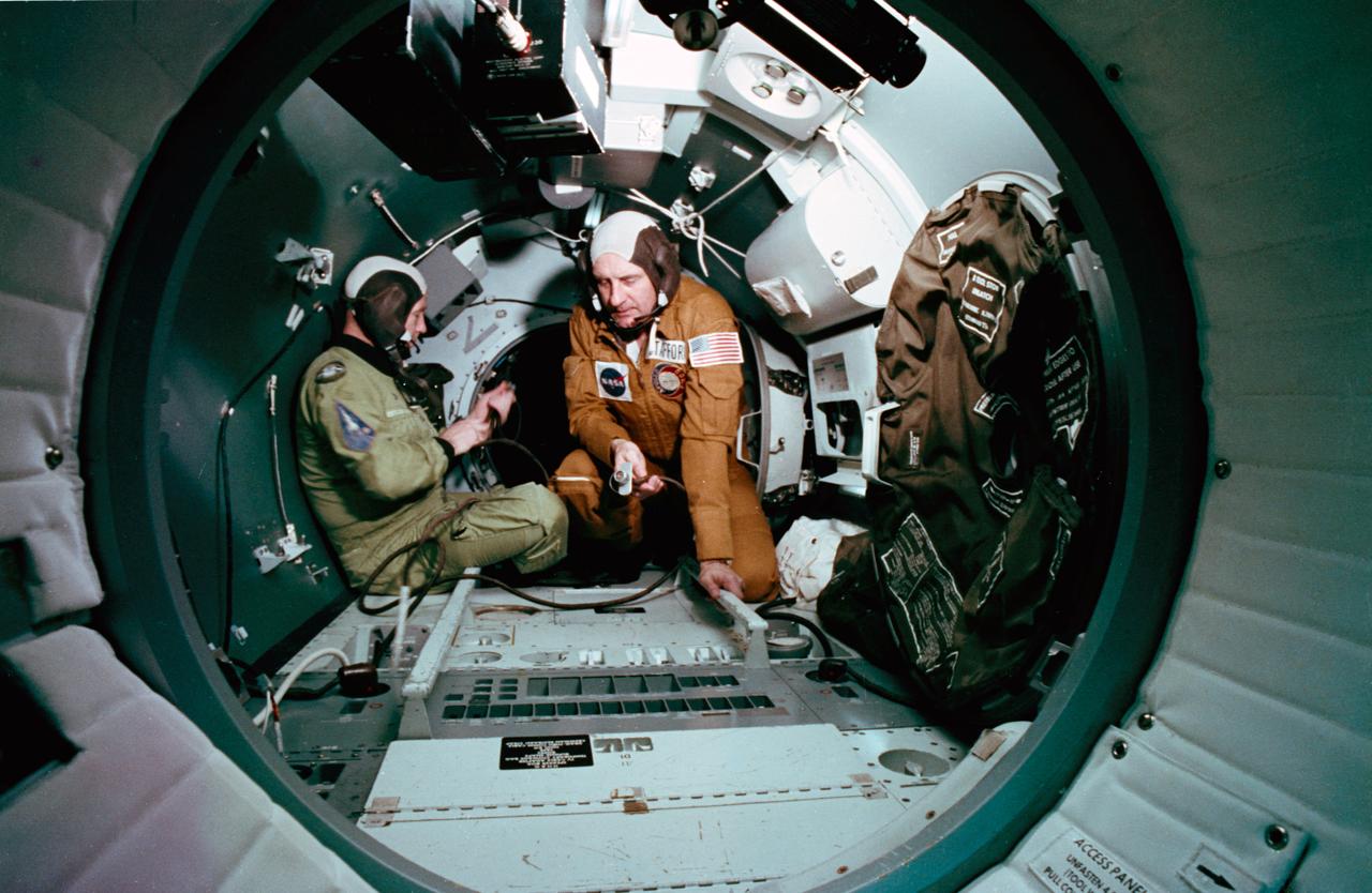 S75-22785 (25 Feb. 1975) --- An interior view of the Docking Module trainer, in Building 35, during Apollo-Soyuz Test Project (ASTP) joint crew training at NASA's Johnson Space Center (JSC). Astronaut Thomas P. Stafford, commander of the American ASTP prime crew, is on the right. The other crewman is cosmonaut Aleksky A. Leonov, commander of the Soviet ASTP prime crew. The training session simulated activities on the second day in Earth orbit.  The American and Soviet crews will visit each other's spacecraft during the July 1975 docking mission in Earth orbit. The Docking Module is designed to link the Apollo and Soyuz spacecraft.