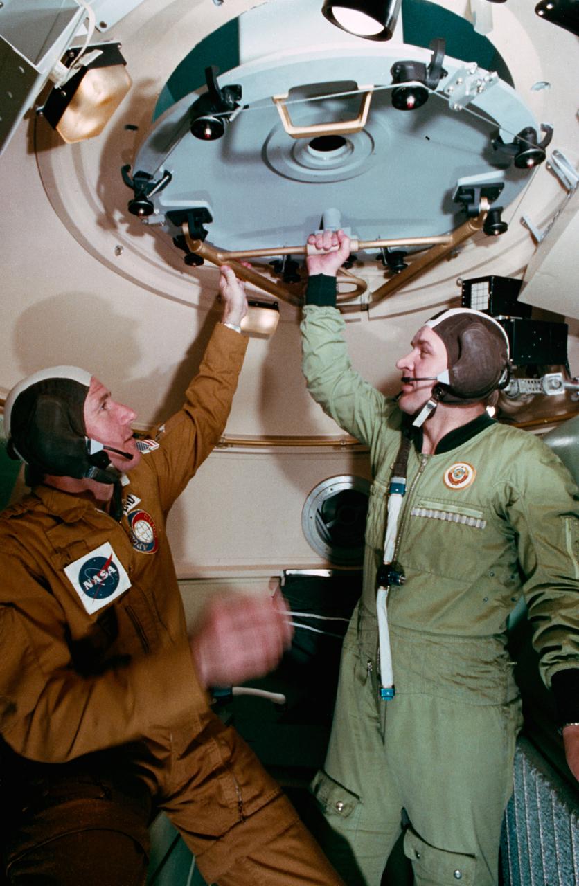 S75-22856 (25 Feb. 1975) --- An interior view of the Soyuz orbital module mock-up in Building 35 during Apollo-Soyuz Test Project joint crew training at NASA's Johnson Space Center. The ASTP crewmen are astronaut Vance D. Brand (on left), command module pilot of the American ASTP prime crew; and cosmonaut Valeriy N. Kubasov, engineer on the Soviet ASTP first (prime) crew. The training session simulated activities on the second day in Earth orbit. Photo credit: NASA