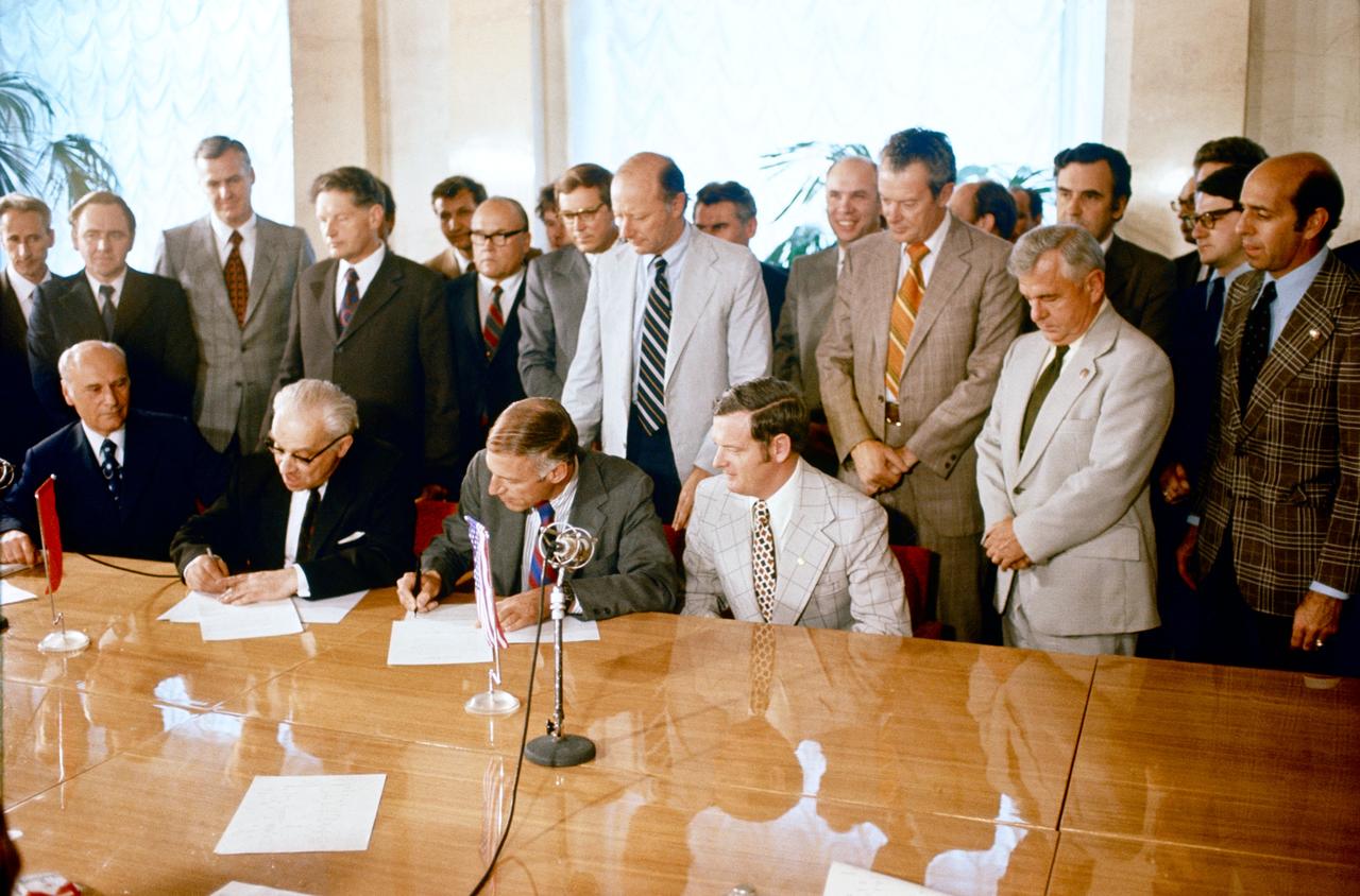 S75-27346 (22 May 1975) --- An overall view of the signing of the Apollo-Soyuz Test Project joint flight readiness review in ceremonies on May 22, 1975 in Moscow. Academician Vladimir A. Kotelnikov (on left) and NASA Deputy Administrator George M. Low (in center) are seen affixing their signatures to the ASTP document. Kotelnikov is the Acting President of the USSR Academy of Sciences. Seated at far left is Professor Konstantin D. Bushuyev, the Soviet Technical Director of ASTP. Dr. Glynn S. Lunney, the U.S. Technical Director of ASTP, is seated on Dr. Low?s left. Arnold W. Frutkin (in light jacket), NASA Assistant Administrator for International Affairs, is standing behind Dr. Low. Academician Boris N. Petrov (in dark suit), Chairman of the USSR Council for International Cooperation in the Exploration and Use of Outer Space, is standing behind Kotelnikov. The signing of the agreement took place at the Presidium of the Academy of Sciences in Moscow.