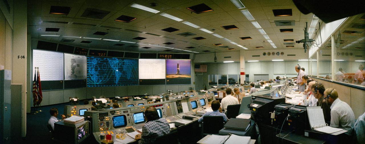 S75-28519 (15 July 1975) --- An overall view of the Mission Operations Control Room in the Mission Control Center, Building 30, Johnson Space Center, on the first day of the Apollo-Soyuz Test Project docking mission in Earth orbit. This photograph was taken shortly before the American ASTP launch from the Kennedy Space Center. The television monitor in the center background shows the ASTP Apollo-Saturn 1B space vehicle on Pad B at KSC?s Launch Complex 39. The American ASTP liftoff followed the Soviet ASTP launch of the Soyuz space vehicle from Baikonur, Kazakhstan by seven and one-half hours.