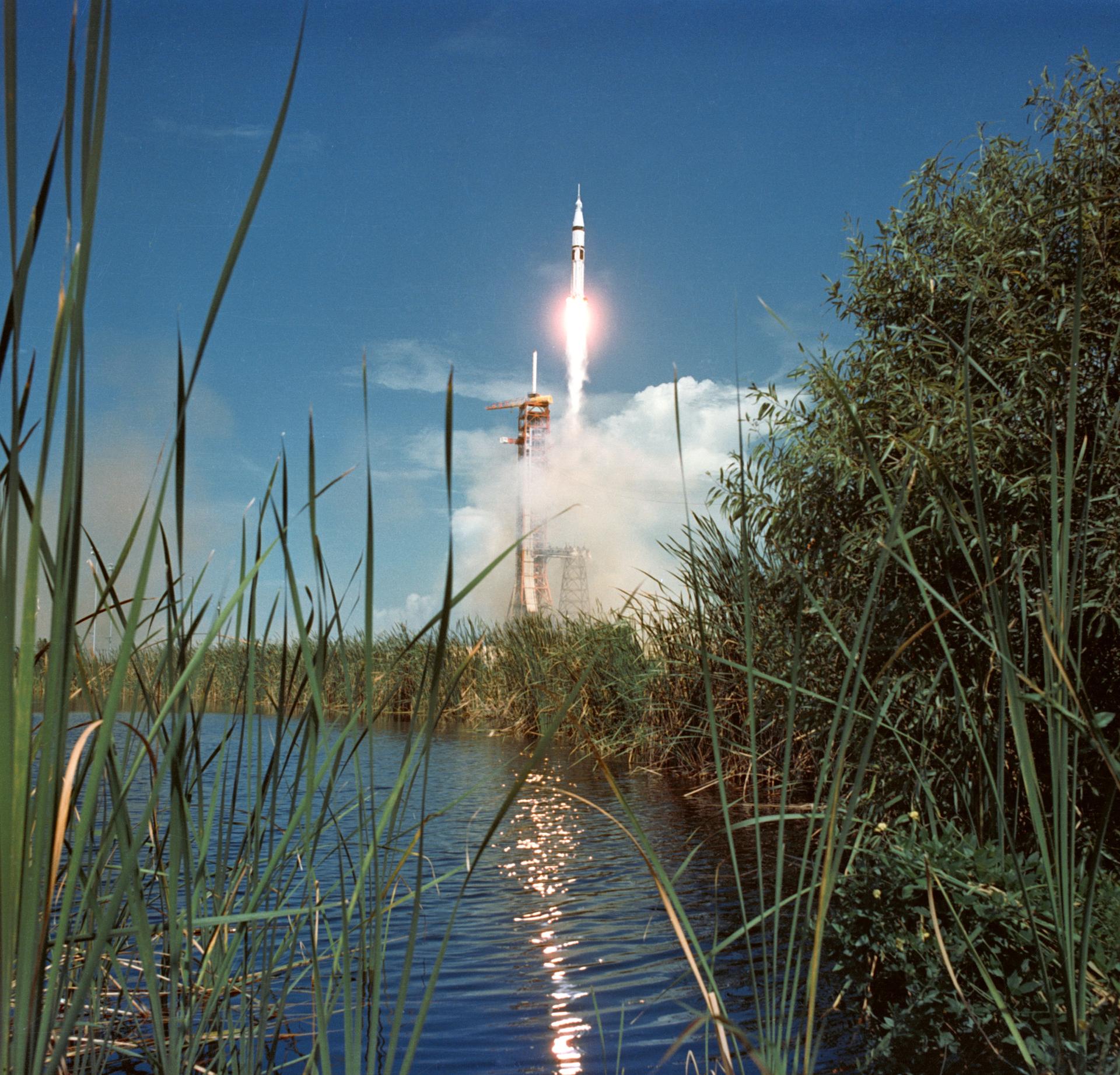 Launch of the Apollo/Saturn 1B space vehicle with greenery and water in the foreground