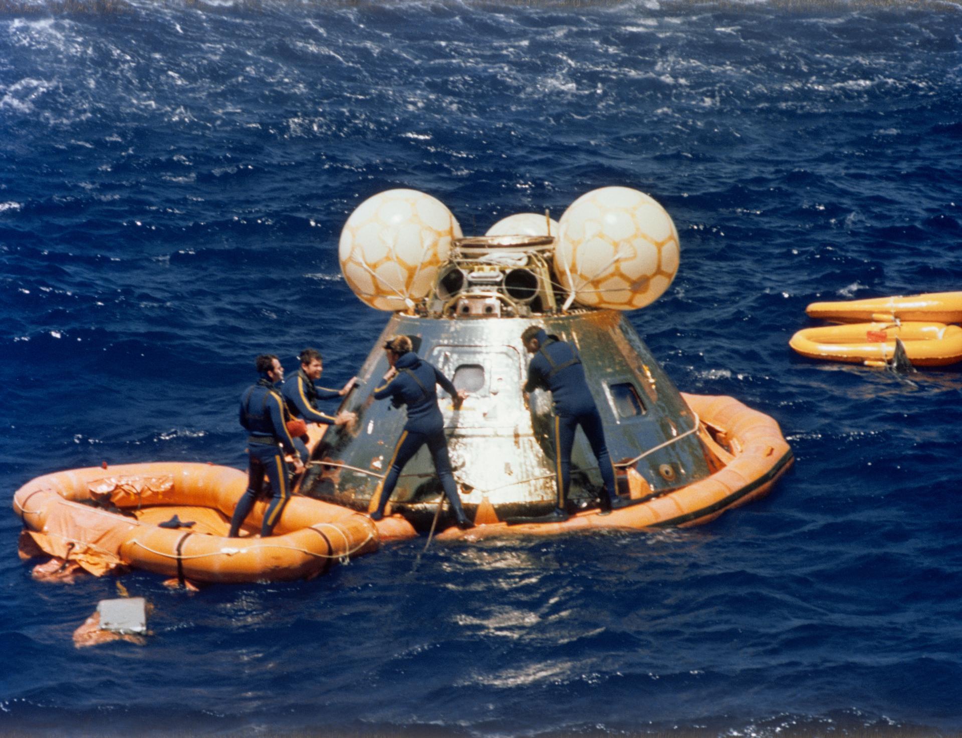 Divers assist with the Apollo command module after splashdown