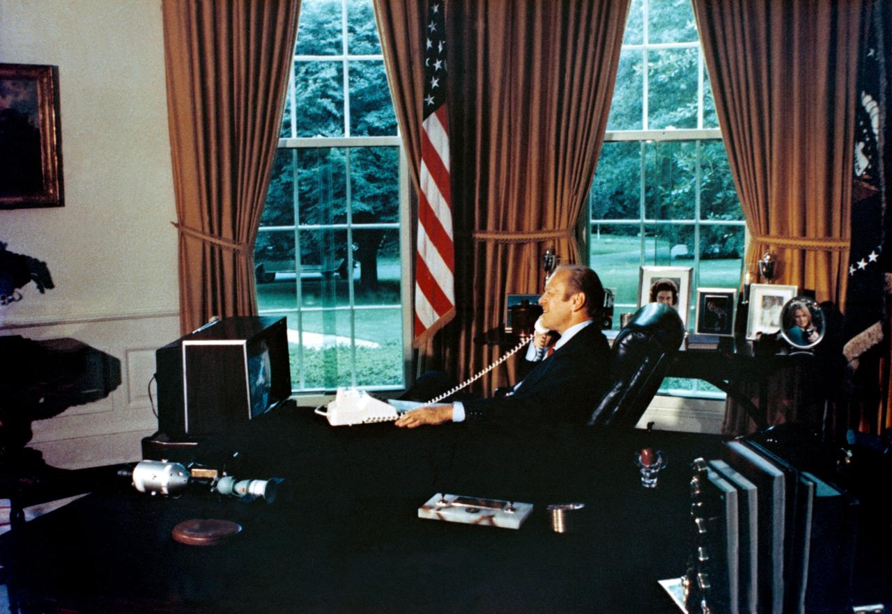 S75-30515 (18 July 1975) --- President Gerald R. Ford watches ASTP crewmen Thomas P. Stafford, Donald K. Slayton and Valeriy N. Kubasov on television as he talks to them via radio-telephone while they orbited Earth on July 18, 1975. The American Apollo spacecraft and Soviet Soyuz spacecraft were docked. The five ASTP crewmen visited each other?s spacecraft while the Soyuz and Apollo were linked in space.