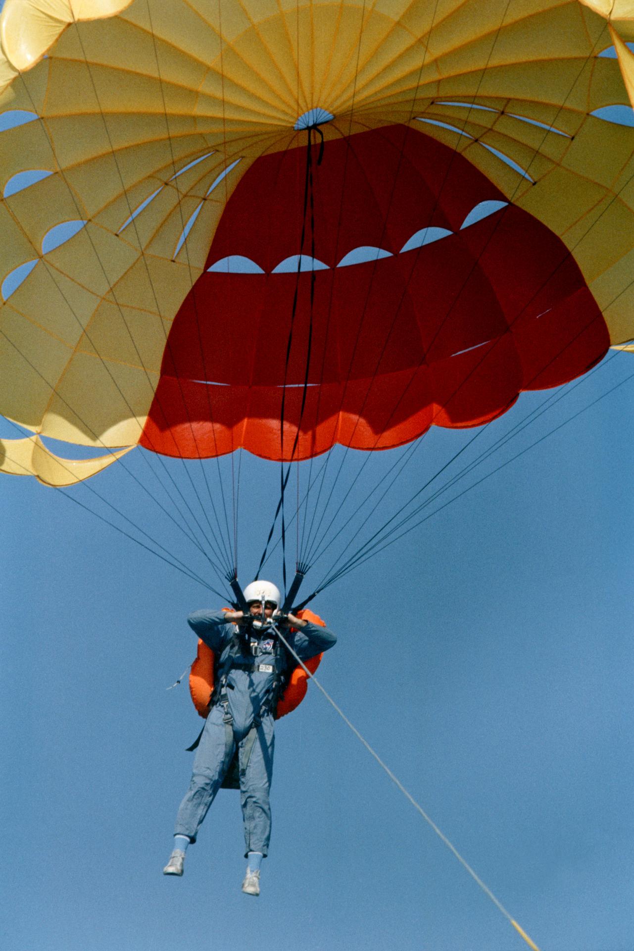 Jack Lousma is strapped to a parachute while behind pulled behind a boat for water survival training