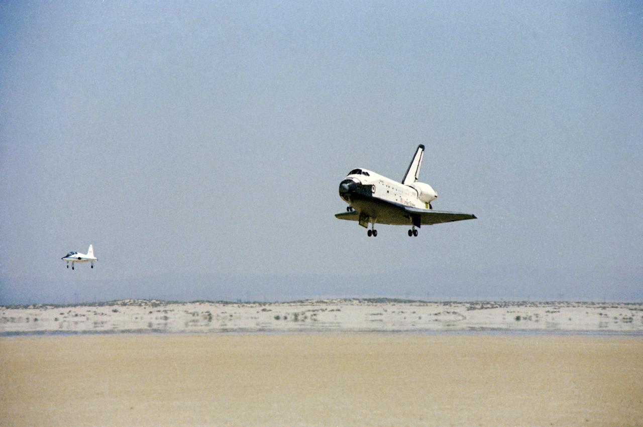 S81-30425 (14 April 1981) --- The space shuttle orbiter Columbia is seen from the front as it heads for a touchdown atop a dry lake bed at Edwards Air Force Base in southern California. A T-38 chase plane follows it in at left. Aboard Columbia were astronauts John W. Young, STS-1 commander, and Robert L. Crippen, pilot. Their landing marked the completion of a successful two-and-a-third day flight in space and the beginning of a new era of space transportation. A series of additional test flights will follow before the Space Shuttle Program becomes fully operational later in this decade. Photo credit: NASA
