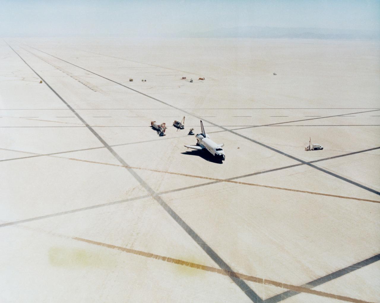 S81-30749 (14 April 1981) --- This high angle view shows the scene at Edwards Air Force Base in southern California soon after the successful landing of the space shuttle orbiter Columbia to end STS-1. Service vehicles approach the spacecraft to perform evaluations for safety, egress preparedness, etc. Astronauts John W. Young, commander, and Robert L. Crippen, pilot, are still inside the spacecraft. Photo credit: NASA