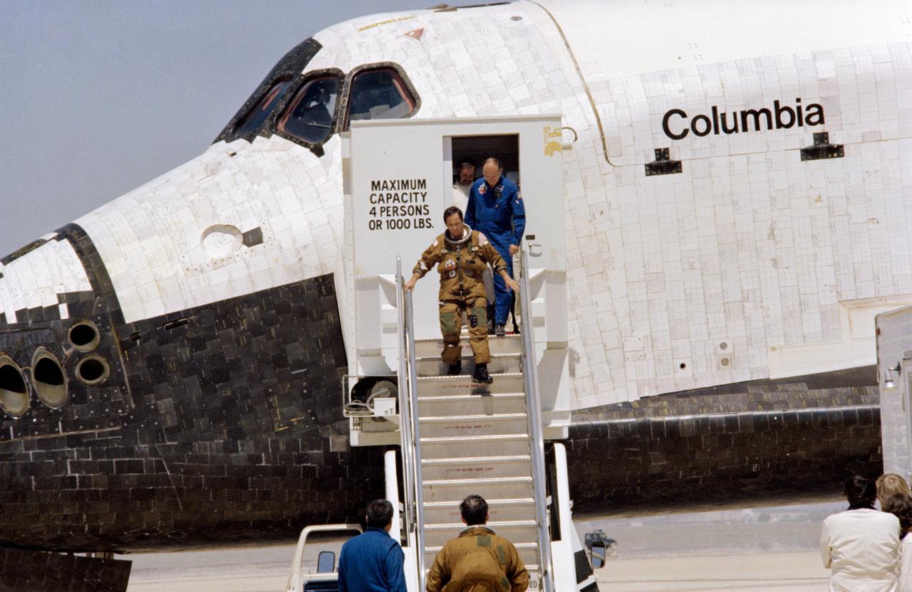 S81-30852 (14 April 1981) --- Astronaut Robert L. Crippen, pilot for the STS-1 flight, egresses the NASA space shuttle following touchdown of the Columbia on Rogers Dry Lake at Edwards Air Force Base, California. Astronaut John W. Young, crew commander, had earlier exited the craft and can be seen standing at the foot of the steps with George W.S. Abbey, director of flight operations at the Johnson Space Center (JSC). Dr. Craig L. Fischer, chief of the medical operations branch in JSC?s medical sciences division, follows Crippen down the steps. Photo credit: NASA