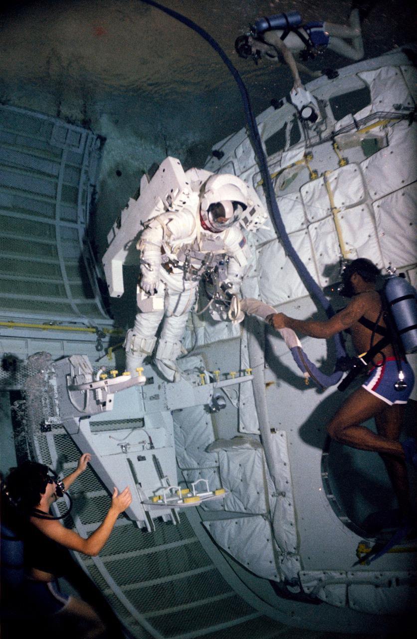 Astronaut Bruce McCandless during an underwater test of the Manned Maneuvering Unit (MMU) Flight Support Station (FSS) donning and doffing in the Bldg 29 Weightless Environment Training Facility (WETF). View is of McCandless wearing the extravehicular mobility unit (EMU), stepping into the MMU.