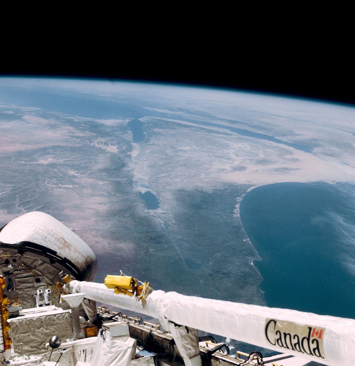 This southerly looking view photographed from the orbiting Space Shuttle Columbia shows a small portion of the vehichle's aft section. The 50-ft Canadian built remote manipulator system (RMS) is in a resting posture (lower right corner) stretched out along the 60-ft. long cargo bay. Many of the components of the OSS-1 payload package are in the bottom center. The Mediterranean Sea is at right foreground. Parts of the Sinai peninsula, Israel, Egypt, Saudi Arabia, Jordan, Palestine, Syria, and Lebanon can be located in the photo. The Red Sea, Gulf of Aqaba, Suez Canal are near the photo's horizon.